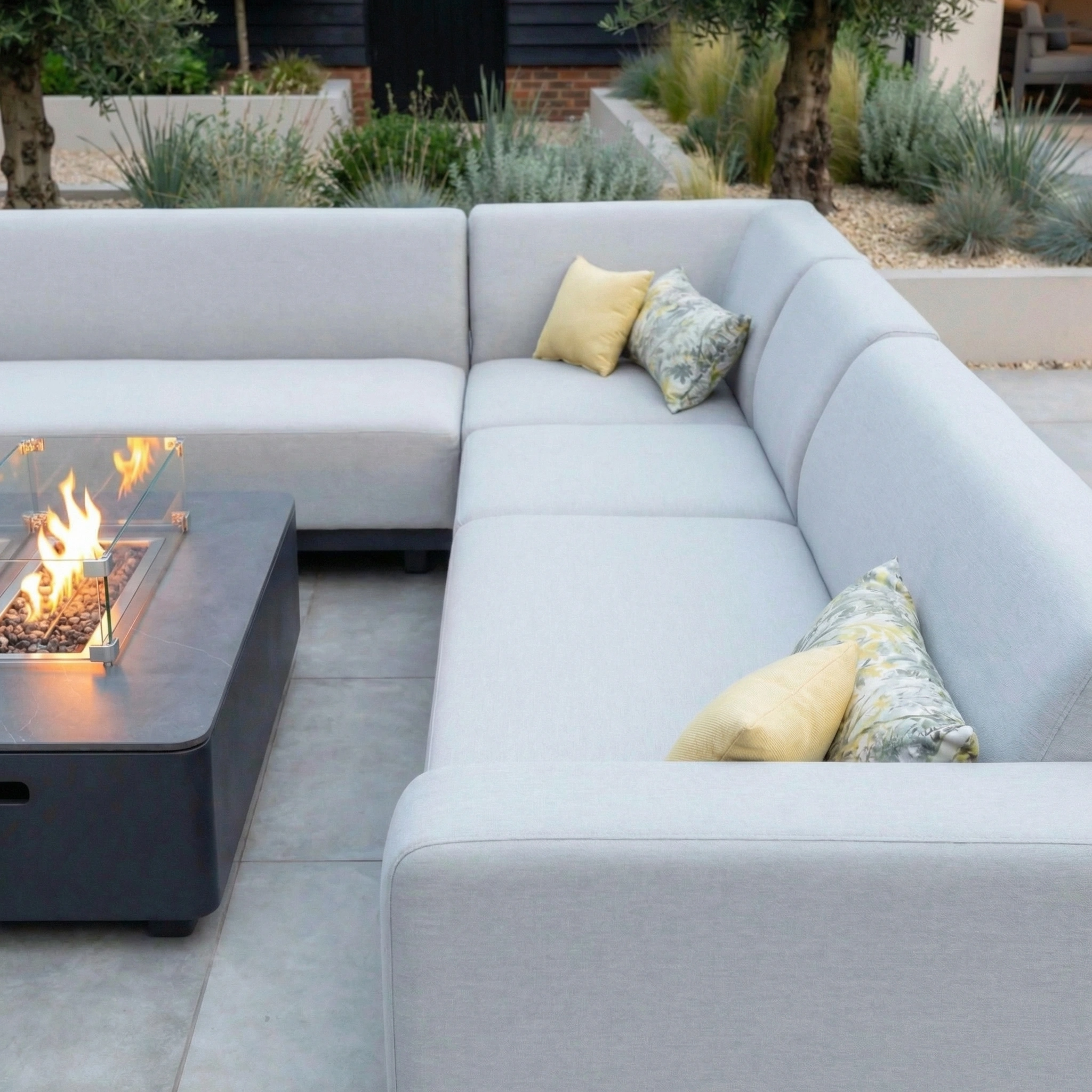 The Luna Outdoor Fabric Large Corner Group Set with Firepit Coffee Table in Oyster Grey features outdoor fabric throw pillows and surrounds a firepit table, creating a modern seating area on your patio.