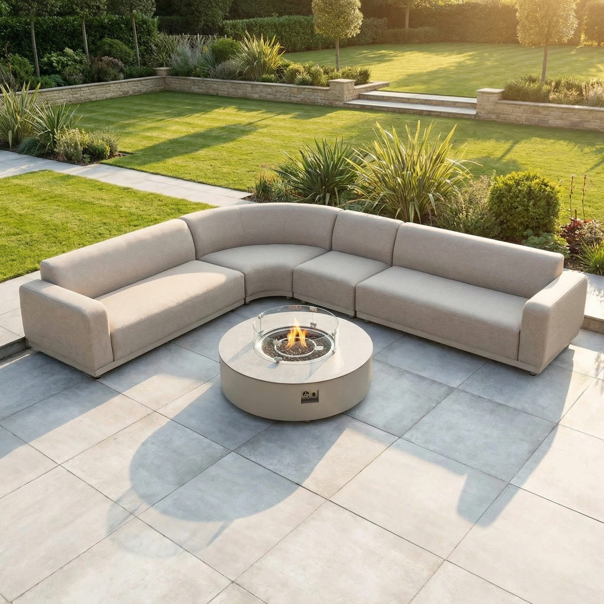 The Luna Outdoor Fabric Large Curved Corner Group Set with Round Firepit Coffee Table in Fawn offers all-weather comfort on modern patios, set against a lush garden backdrop.