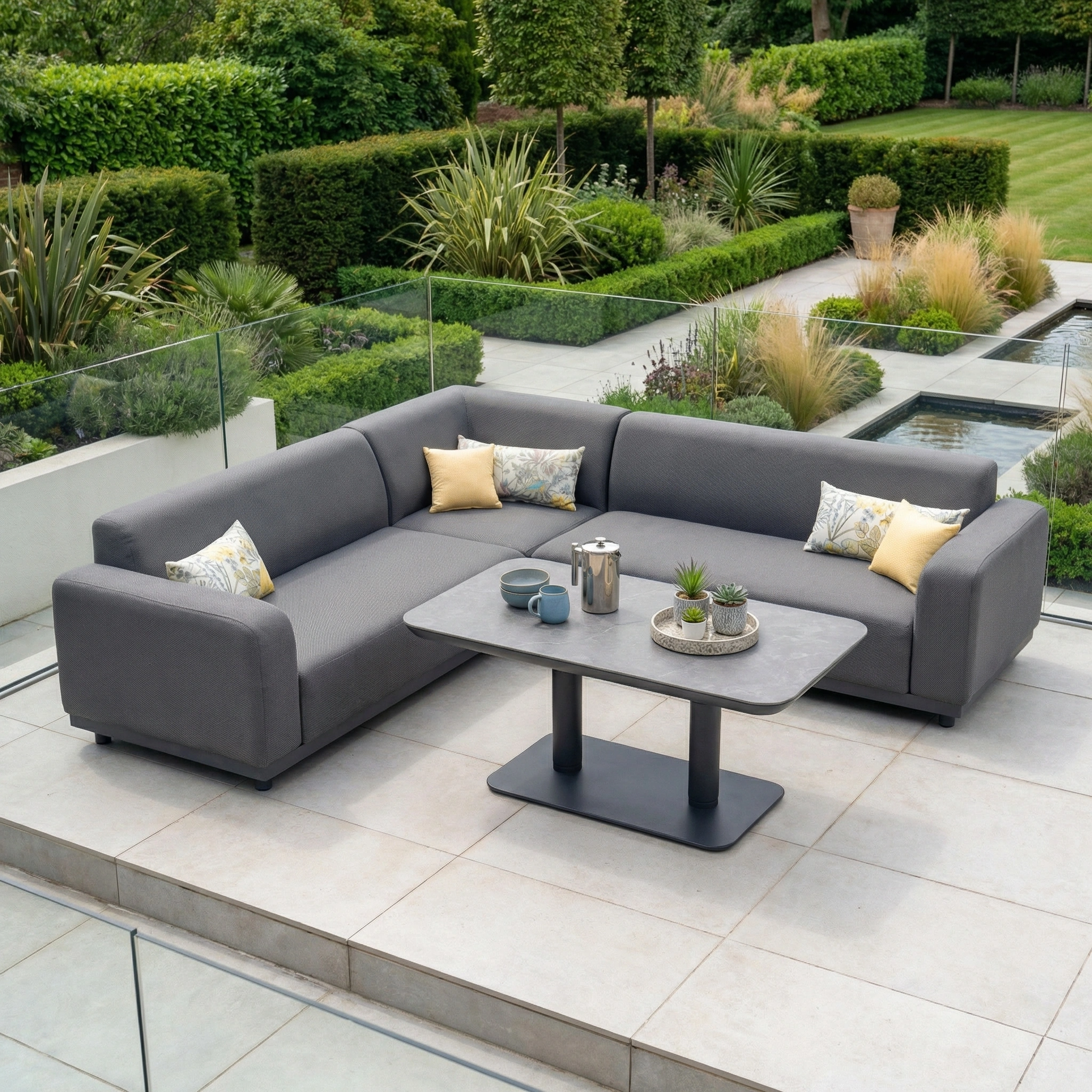 The Luna Outdoor Fabric Corner Sofa Set with Altura Rising Table in Grey features stain-resistant fabric, yellow and patterned pillows, a stylish table, and suits any garden space—combining elegance and practicality for your outdoors.