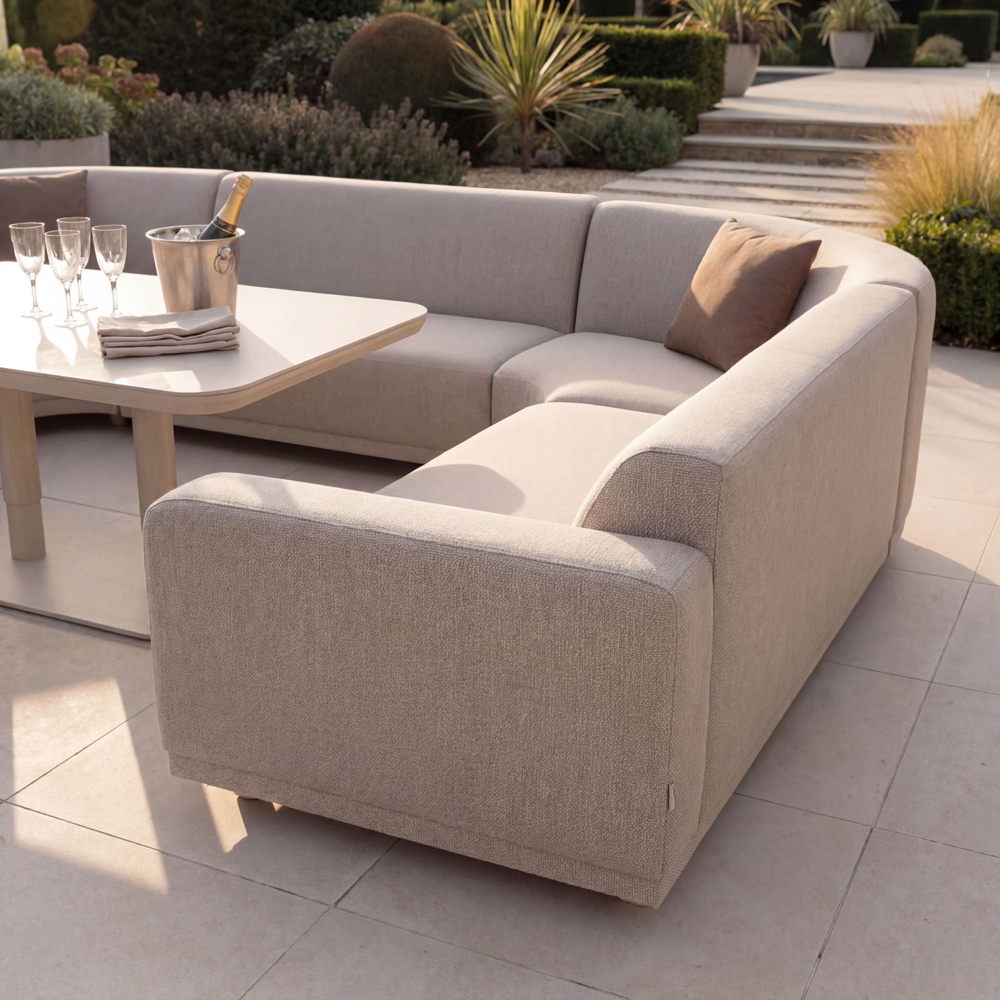 The Luna Outdoor Fabric Curved U-Shape Sofa Set with Altura Rising Table in Fawn features all-weather fabric and comes with four glasses and a champagne bucket, perfect for relaxing on your patio.