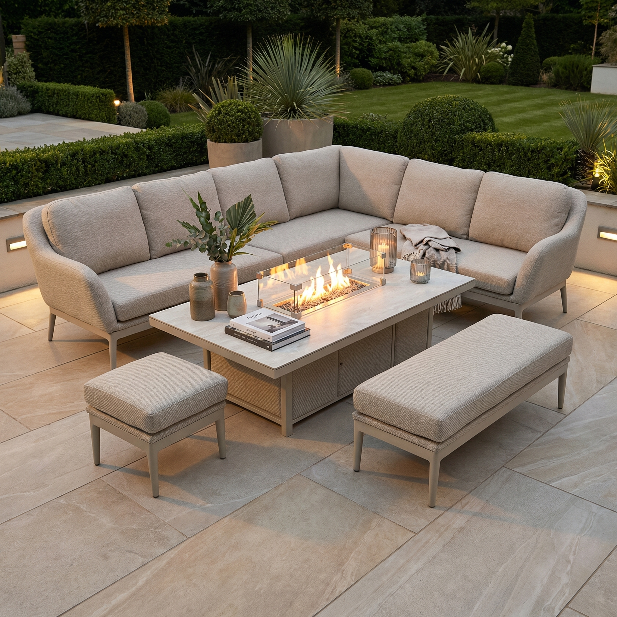 Landscaped garden patio featuring the Luna Outdoor Fabric Rectangular Corner Dining Set with Rising Firepit Table in Fawn (Right Hand), plus bench, ottoman, and potted plants.