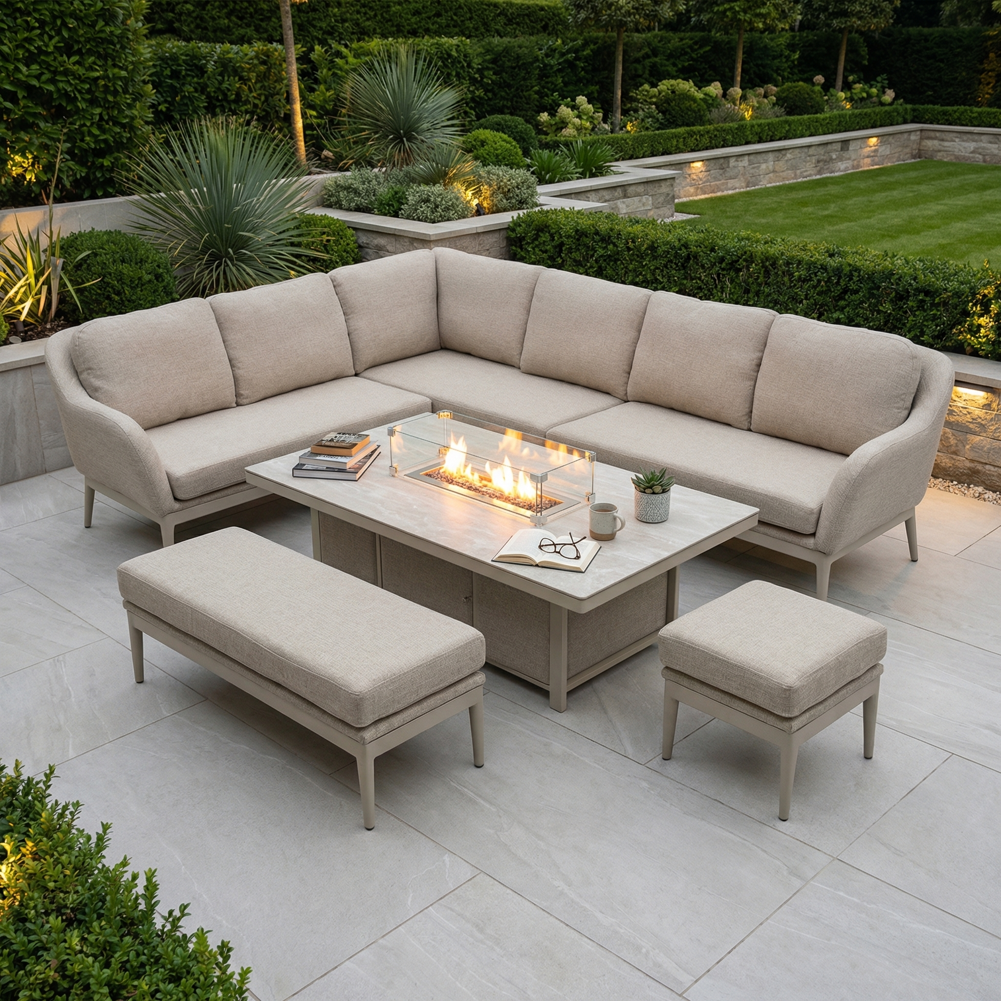 The Luna Outdoor Fabric Rectangular Corner Dining Set with Rising Firepit Table in Fawn (Left Hand) offers stylish, all-weather relaxation on any patio with its sectional sofa, bench, and stool surrounded by lush greenery.