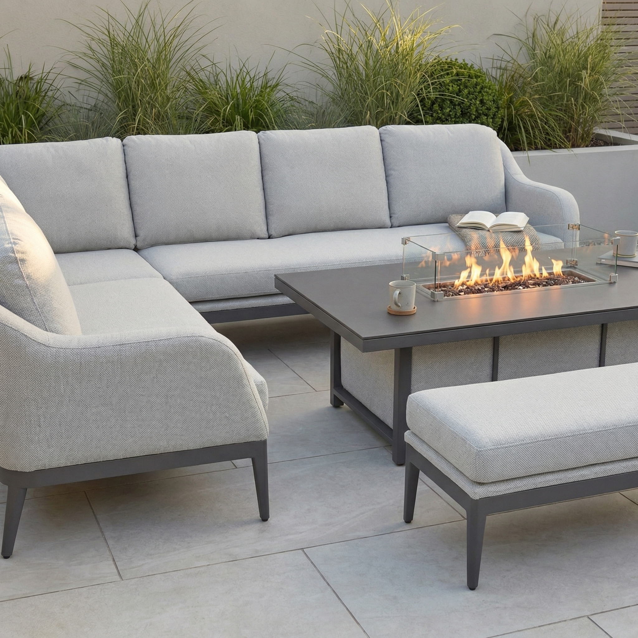 The Luna Outdoor Fabric Rectangular Corner Dining Set with Rising Firepit Table in Oyster Grey (Left Hand) features modern, maintenance-free design and light gray cushions, creating a welcoming retreat for your garden.