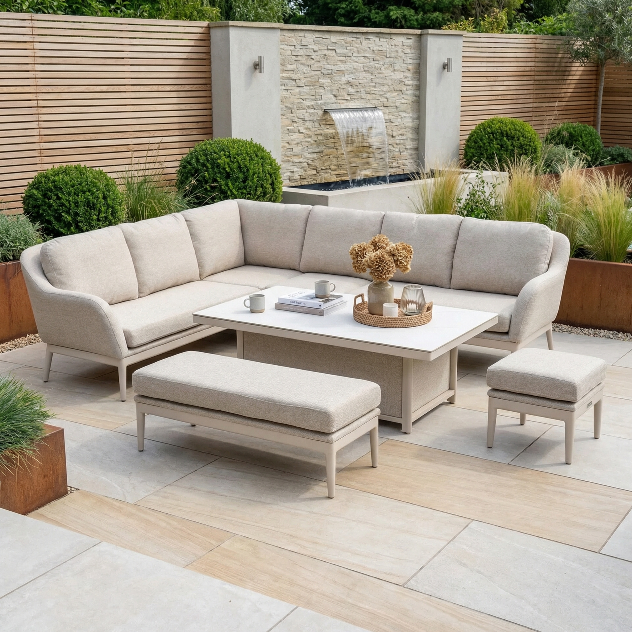 Modern patio with water feature and landscaped garden, showcasing the Luna Outdoor Fabric Rectangular Corner Dining Set with Rising Table in Fawn (Left Hand) for stylish, all-weather comfort and lasting outdoor elegance.