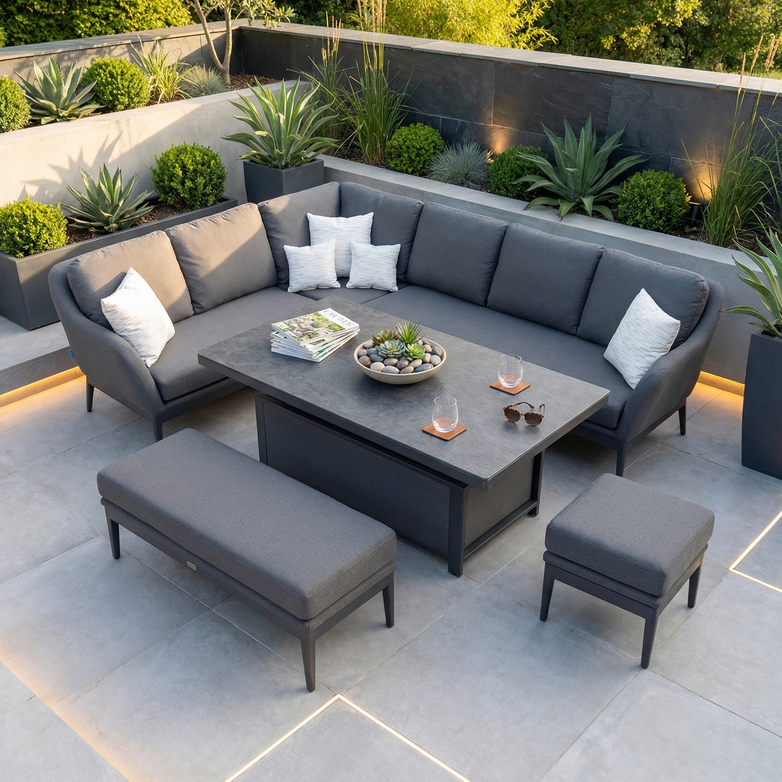 A modern patio with the Luna Outdoor Fabric Rectangular Corner Dining Set with Rising Table in Grey (Left Hand), accented by green plants and soft lighting.