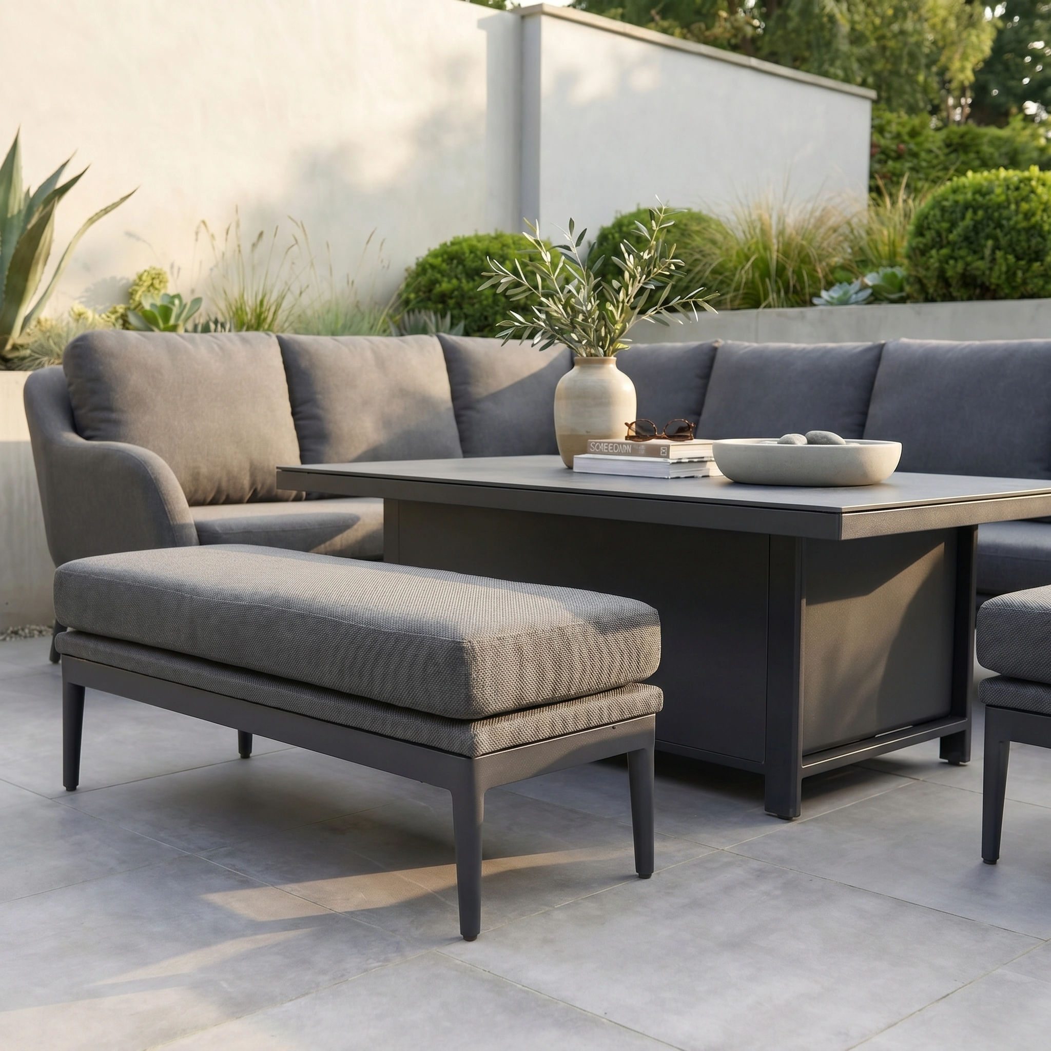 Contemporary garden with the Luna Outdoor Fabric Rectangular Corner Dining Set in Grey (Left Hand), featuring all-weather cushioned seating, a rising table, and potted plants for a stylish patio look.