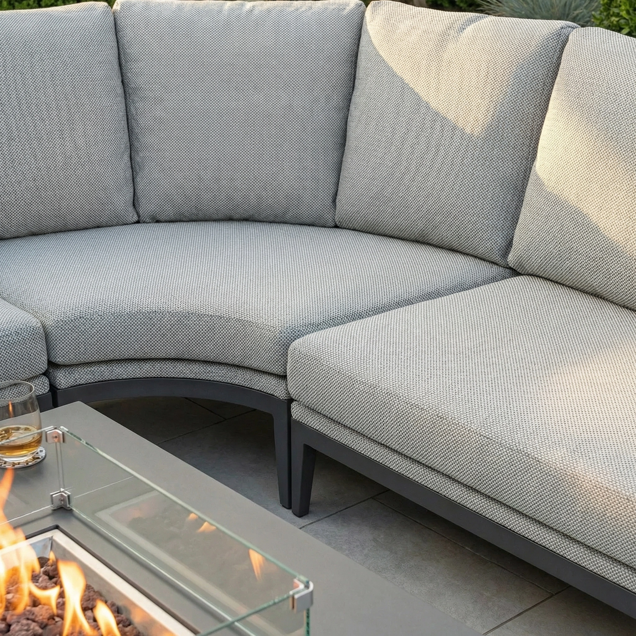 The Luna U-Shape Outdoor Fabric Corner Dining with Rising Firepit Table in Oyster Grey is perfect for relaxing evenings outdoors, offering maintenance-free comfort and a stylish spot to unwind with a drink by the fire.