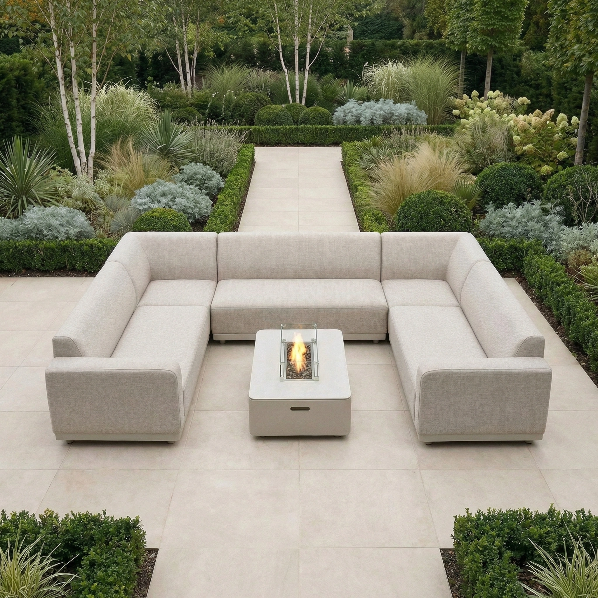 The Luna U-Shape Outdoor Fabric Sofa Set with Firepit Coffee Table in Fawn sits on a tiled patio, surrounded by a lush, manicured garden.