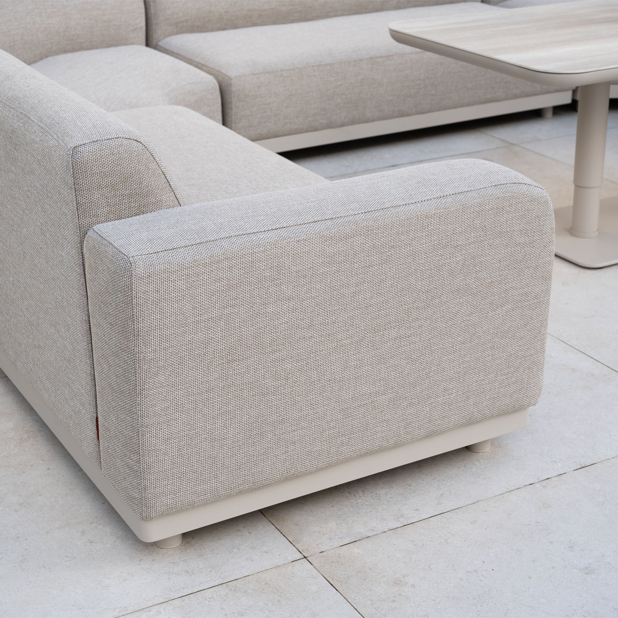 The Luna Outdoor Fabric Curved U-Shape Sofa Set with Altura Rising Table in Fawn forms an inviting all-weather garden ensemble, ideal for tiled floors and outdoor lounging.