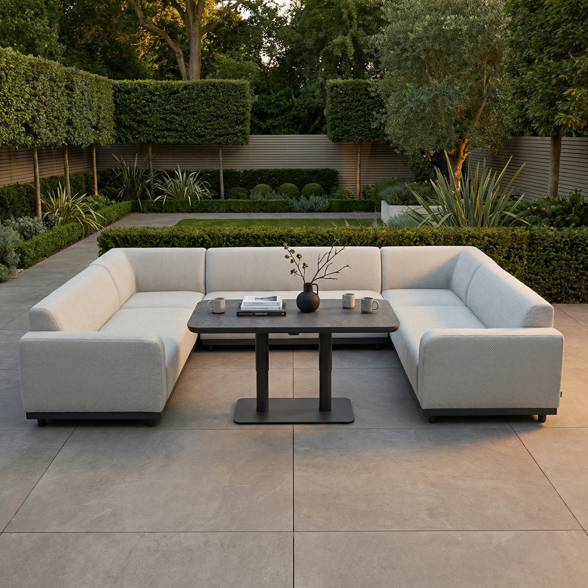 The Luna U-Shape Outdoor Fabric Sofa Set in Oyster Grey with Altura Rising Table features rain-resistant fabric, perfect for modern landscaped gardens.