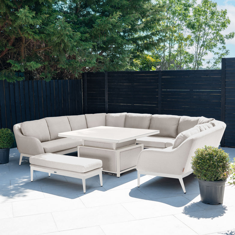 Modern patio featuring the Luna U-Shape Outdoor Fabric Corner Dining with Rising Table in Fawn, a matching bench, and potted plants on a tiled floor.
