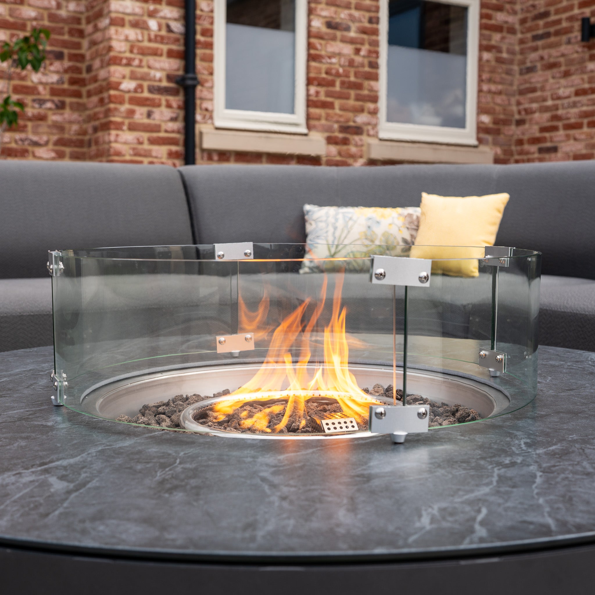 The Luna U-Shape Outdoor Fabric Curved Corner Dining set in grey features a round firepit coffee table, creating a cozy and inviting patio space for relaxing or entertaining.