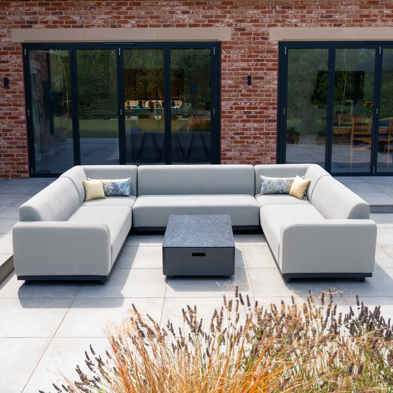 Modern outdoor patio featuring the Luna U-Shape Outdoor Fabric Sofa Set with Coffee Table in Oyster Grey, complete with decorative pillows, on a tiled terrace.