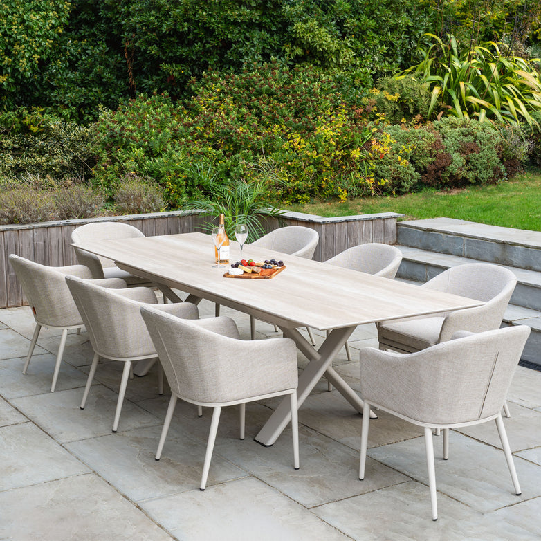 The Luna 8 Seat Outdoor Fabric Dining Set with Albatross Extending Table in Fawn, arranged with wine and snacks, creates an inviting atmosphere on the stone patio.