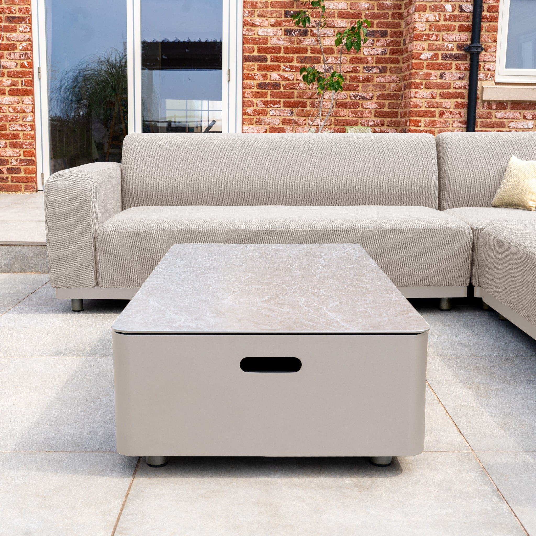 Modern patio with the Luna Outdoor Fabric Corner Sofa Set in Fawn, featuring an all-weather sofa and a rectangular coffee table on a tiled floor.