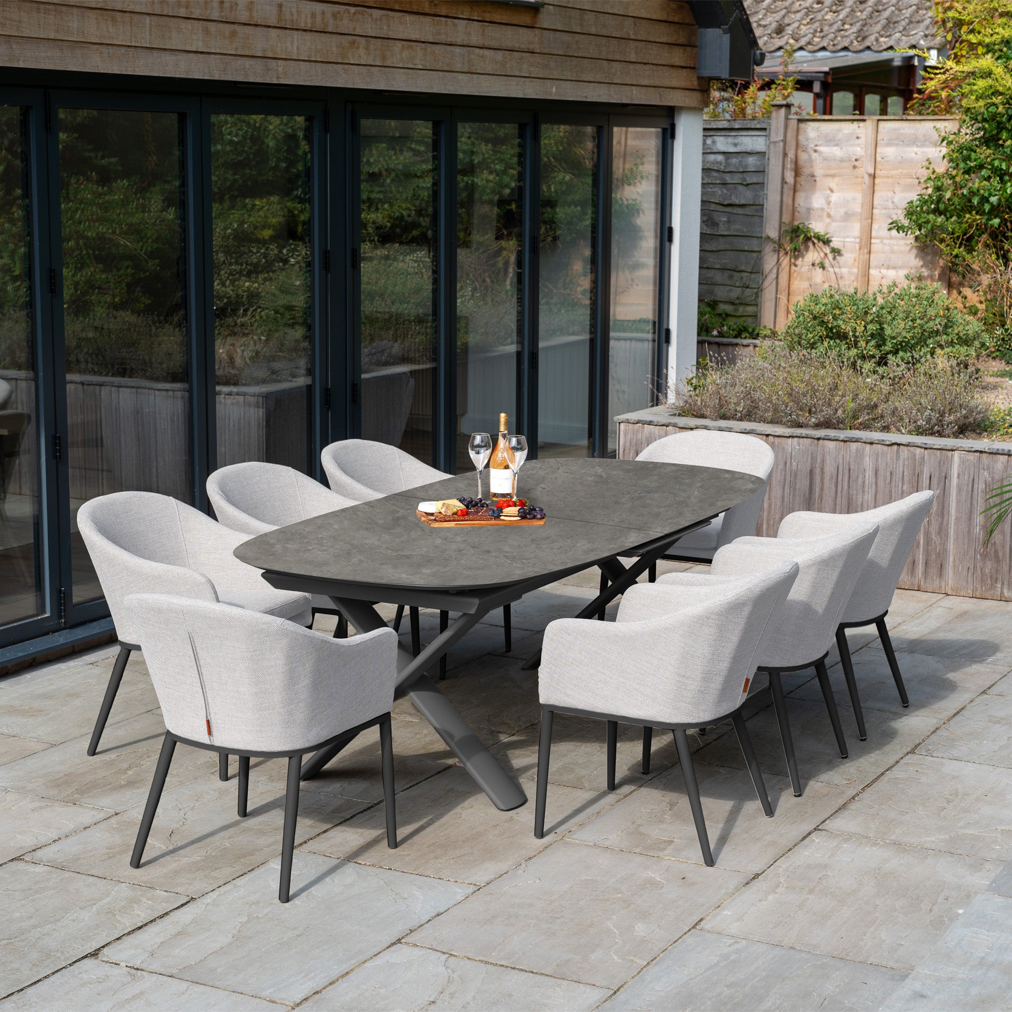 The Luna 8 Seat Outdoor Fabric Oval Dining Set with Albatross Extending Table in Oyster Grey features UV-resistant cushions—ideal for patio gatherings with drinks and snacks.