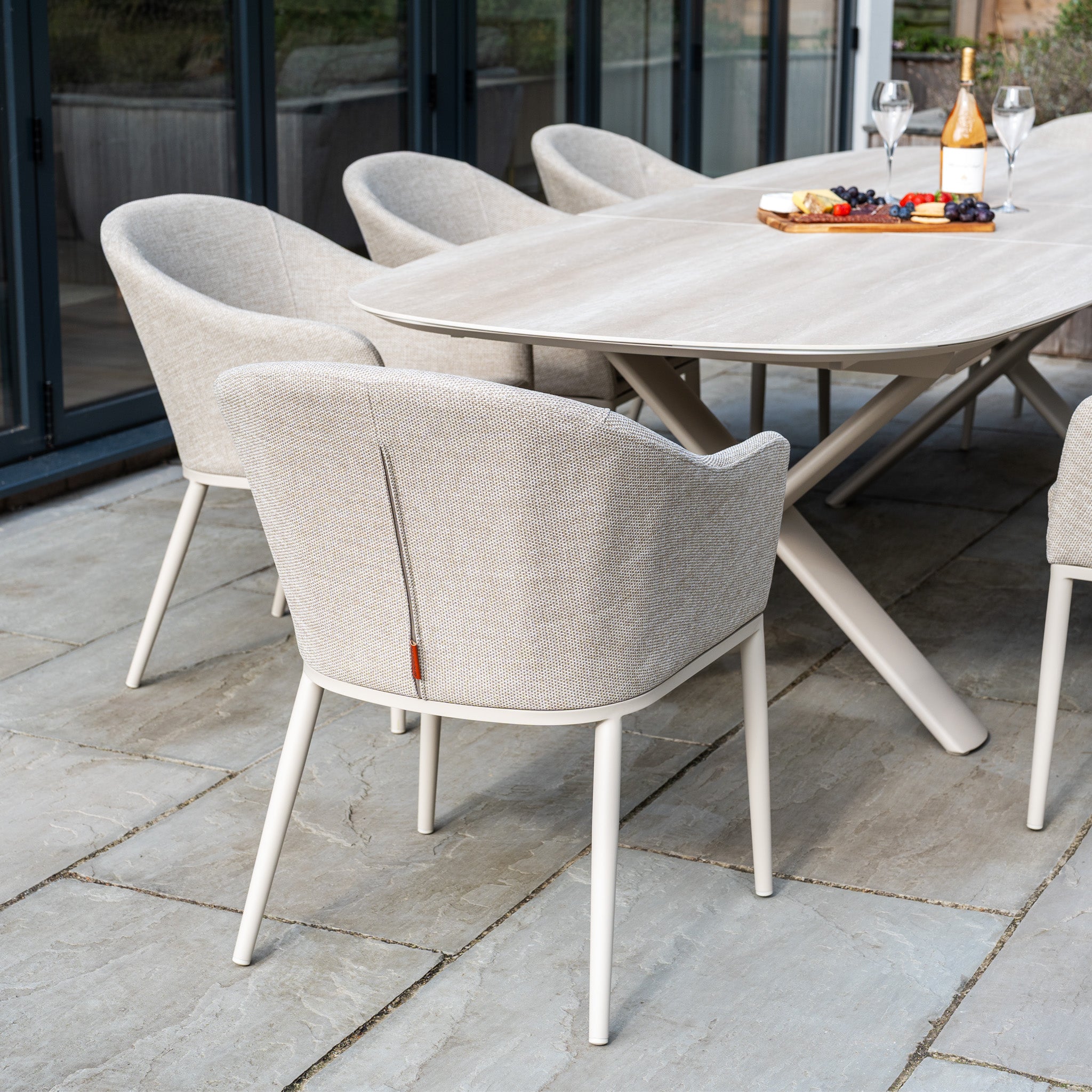 The Luna 8 Seat Outdoor Fabric Oval Dining Set with Albatross Extending Table in Fawn features UV resistant cushions and an extending table, perfect for stylish outdoor dining on a stone patio.