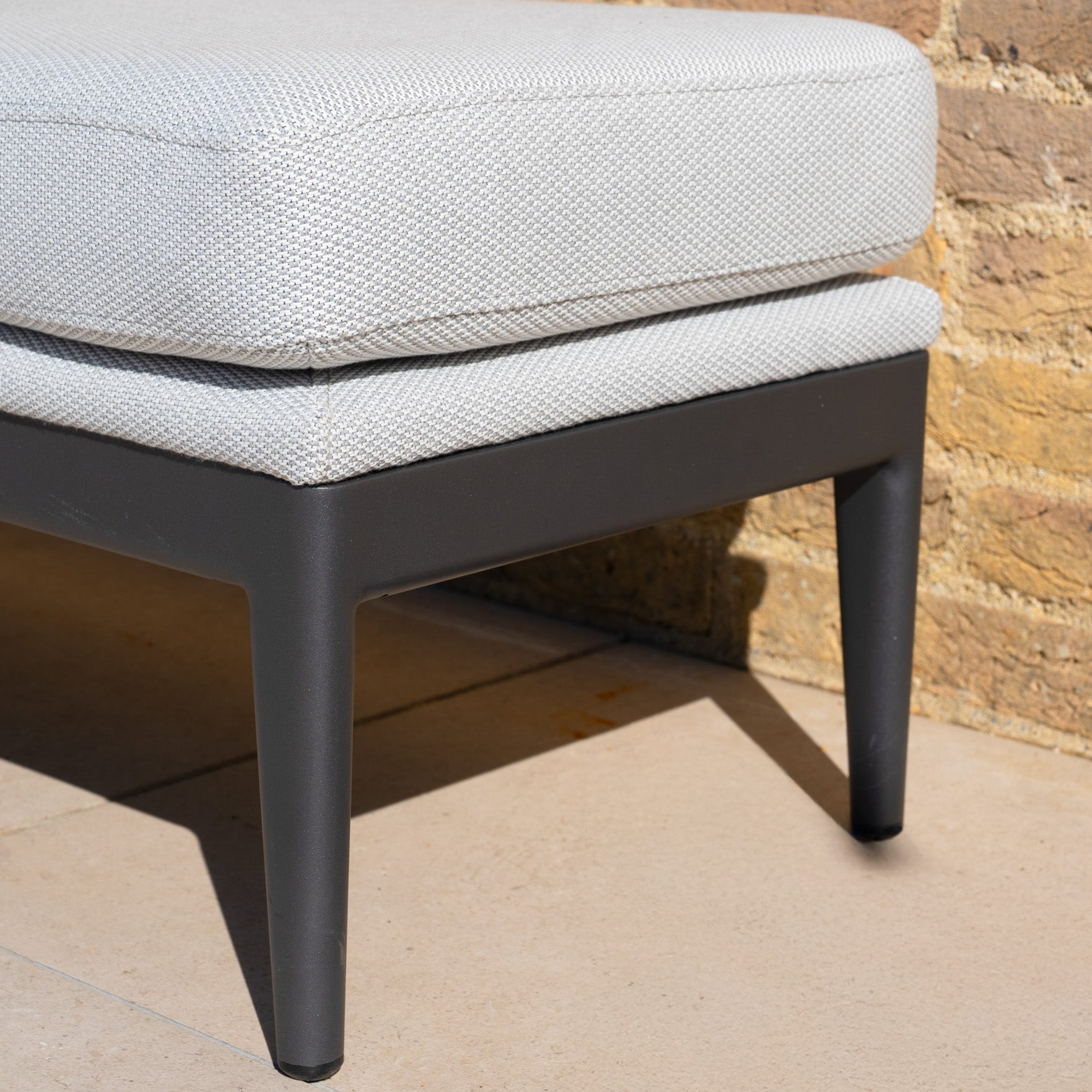 Close-up of the Luna Stool in Oyster Grey featuring quick-dry cushions and black metal legs on a tiled patio, perfect for all-weather outdoor spaces.