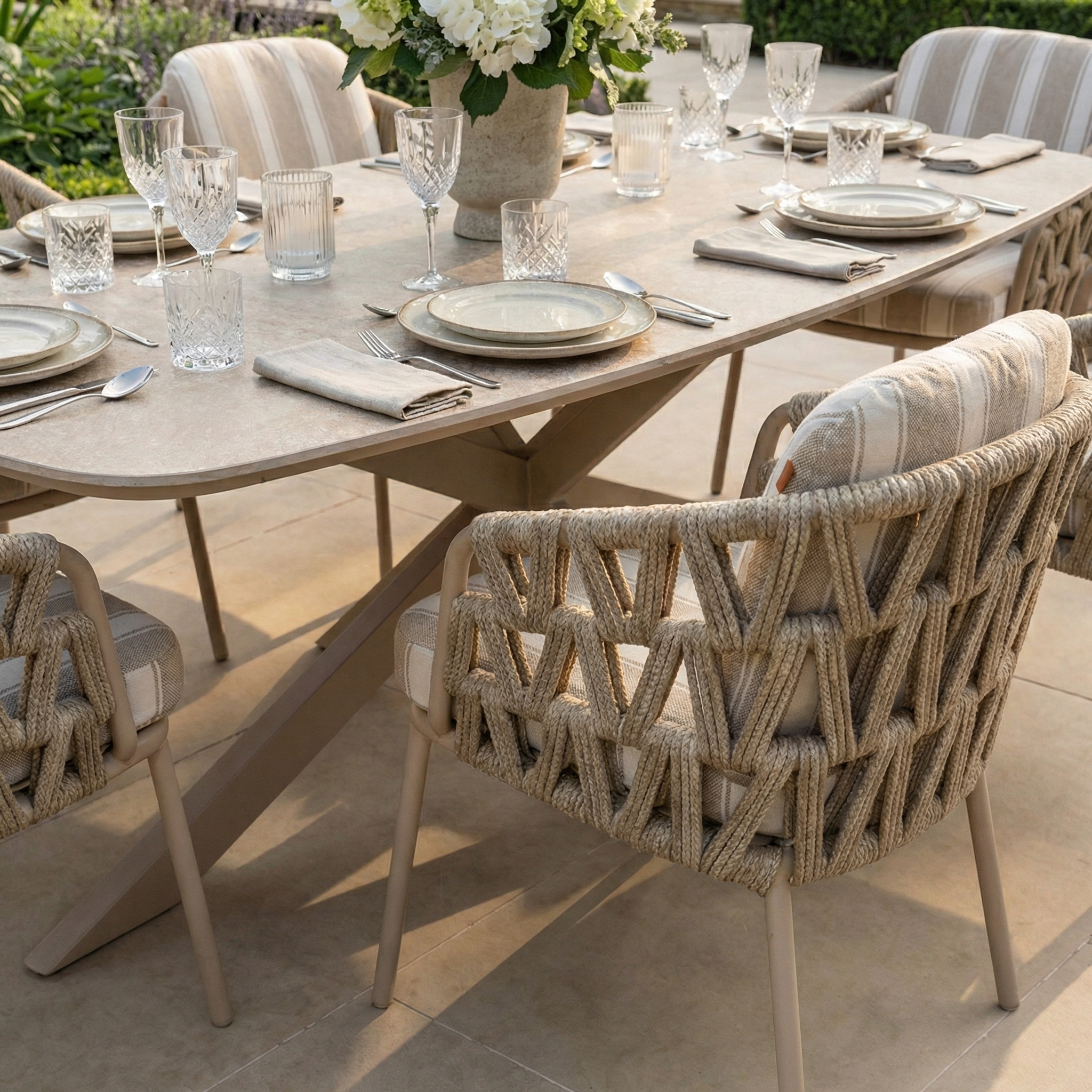 The Madeira 6 Seat Curved Rectangular Dining Set in Striped Latte features a powder-coated aluminium table and cushioned woven chairs, ideal for enjoying gatherings outdoors in natural light.