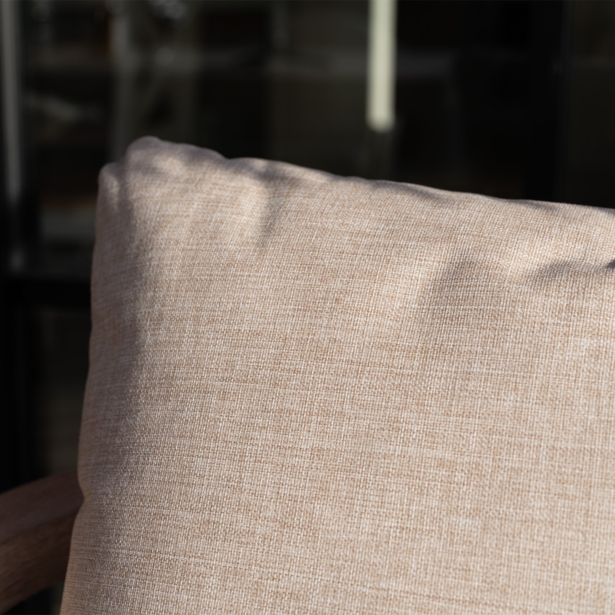 The Quay 4 Seat Round Dining Set in Mocha features a beige textured cushion on a wooden chair, creating an elegant patio ambiance enhanced by natural sunlight.