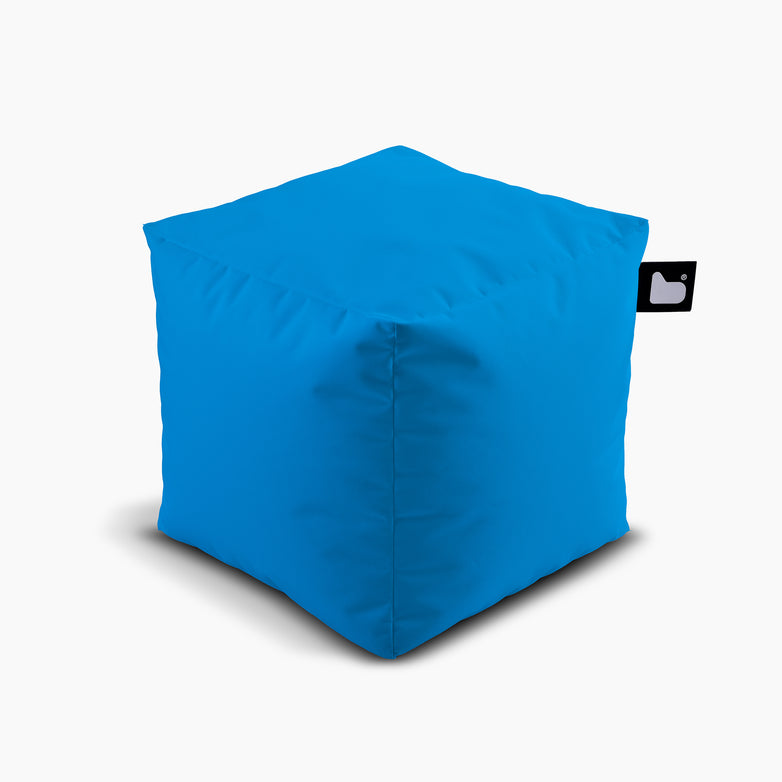 The Outdoor B-Box in Aqua is a bright blue fabric cube ottoman with a small black tag featuring a white heart, perfect for extreme lounging.