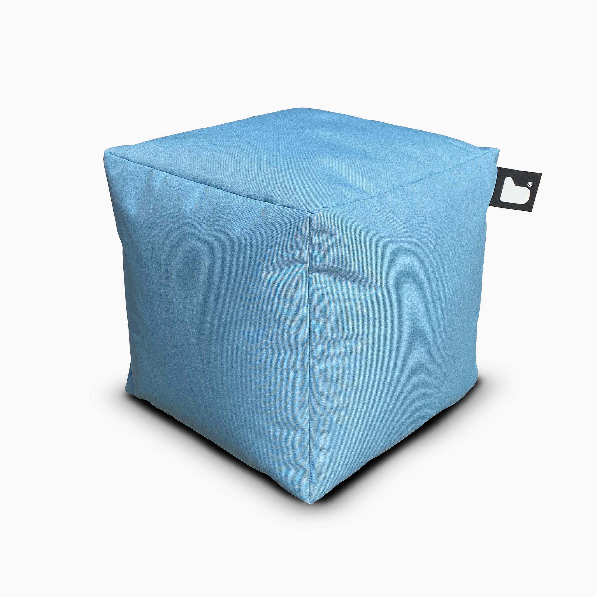 Introducing the Outdoor B-Box in Sea Blue: a light blue fabric cube with a black tag featuring a white heart on one side, designed for extreme lounging, isolated on a white background.