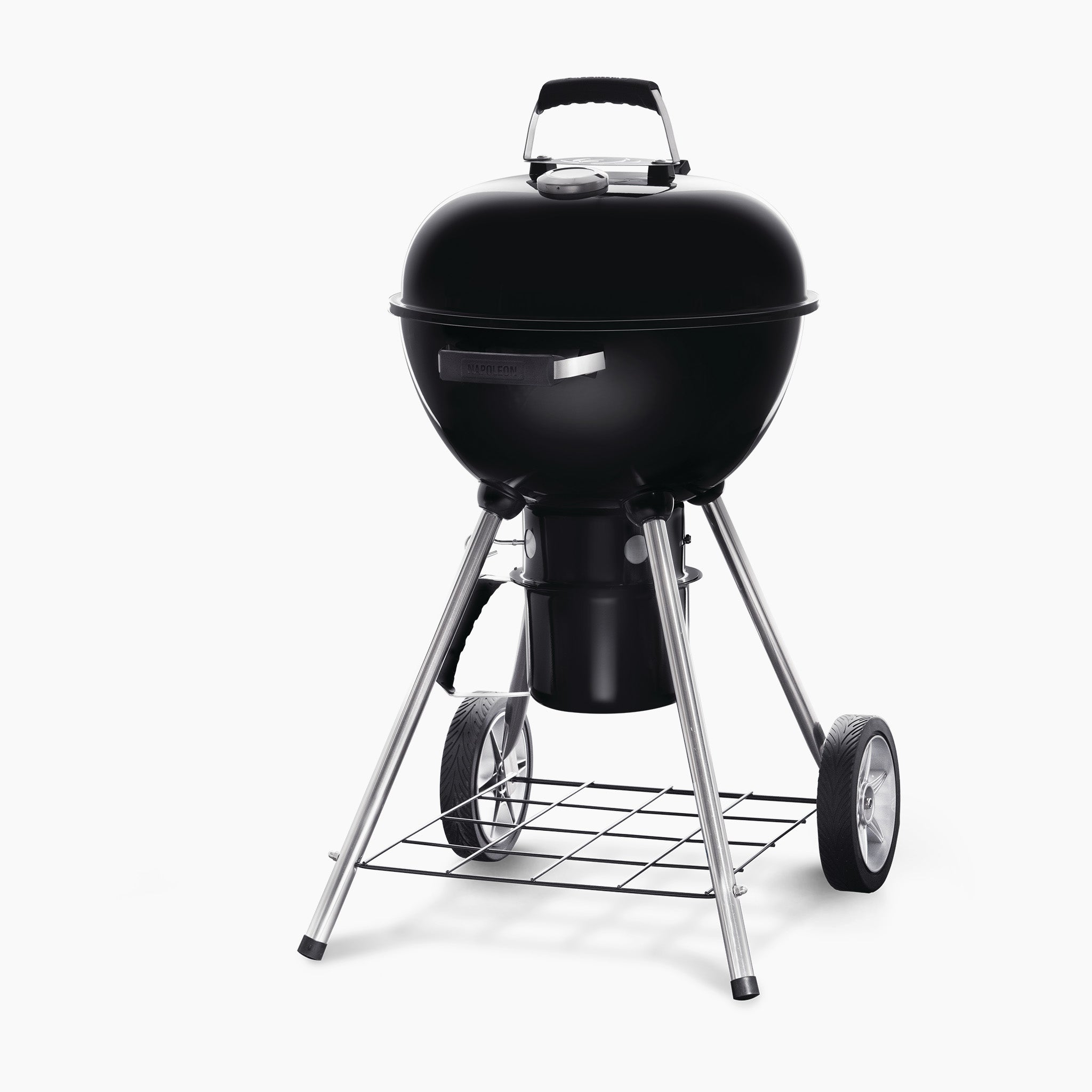 The Napoleon NK18 Charcoal Kettle Grill is a black, round charcoal grill on a stand with two wheels for mobility, featuring adjustable vents and a metal grid for storage at the bottom.