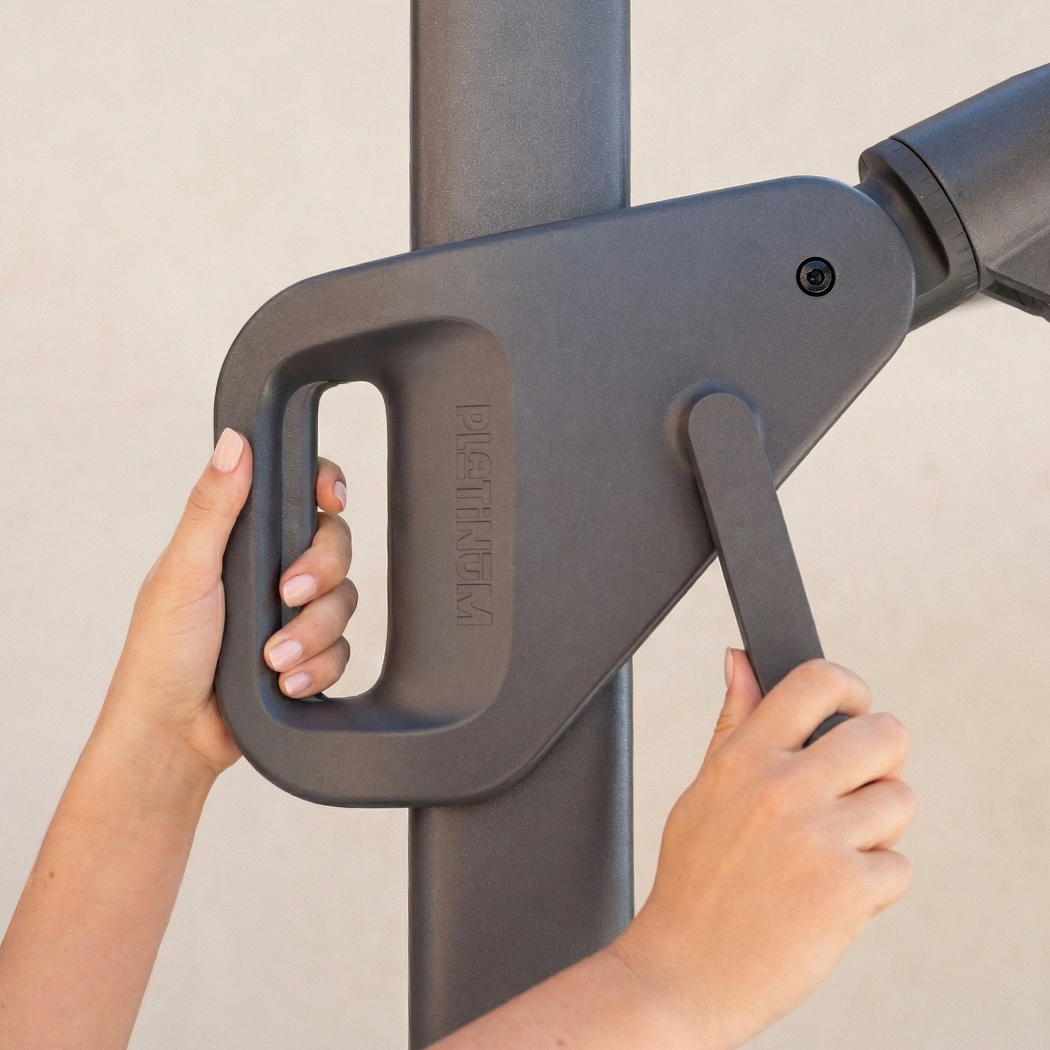 Close-up of hands operating a crank handle on the Nexus T2 Premium 3m Square Cantilever Parasol in Black with 90kg Granite Base.