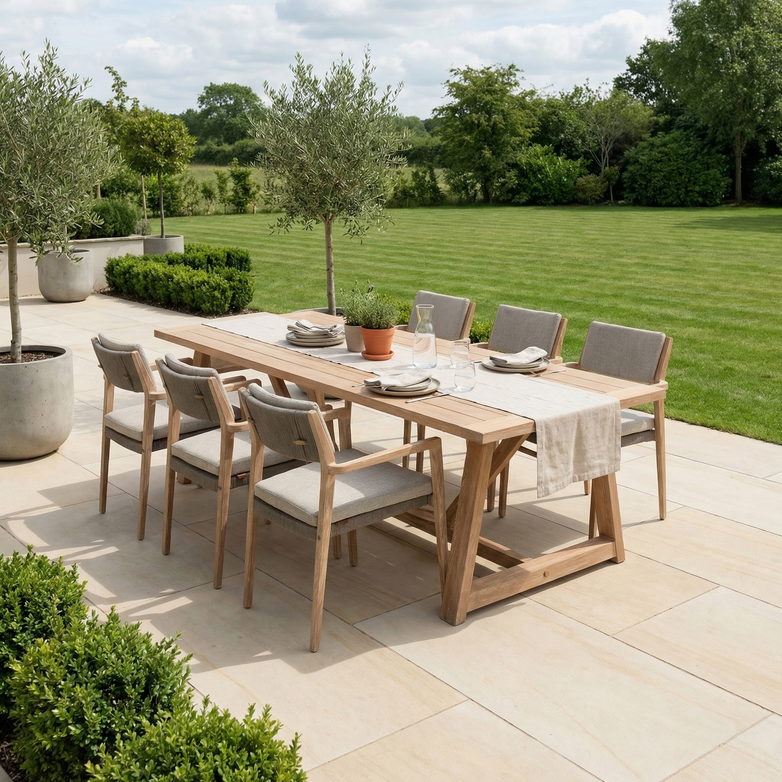 The Noah 6 Seat Rectangular Dining Set in Volga Grey is arranged on a patio with views of a green lawn and trees, creating an inviting space for outdoor gatherings.