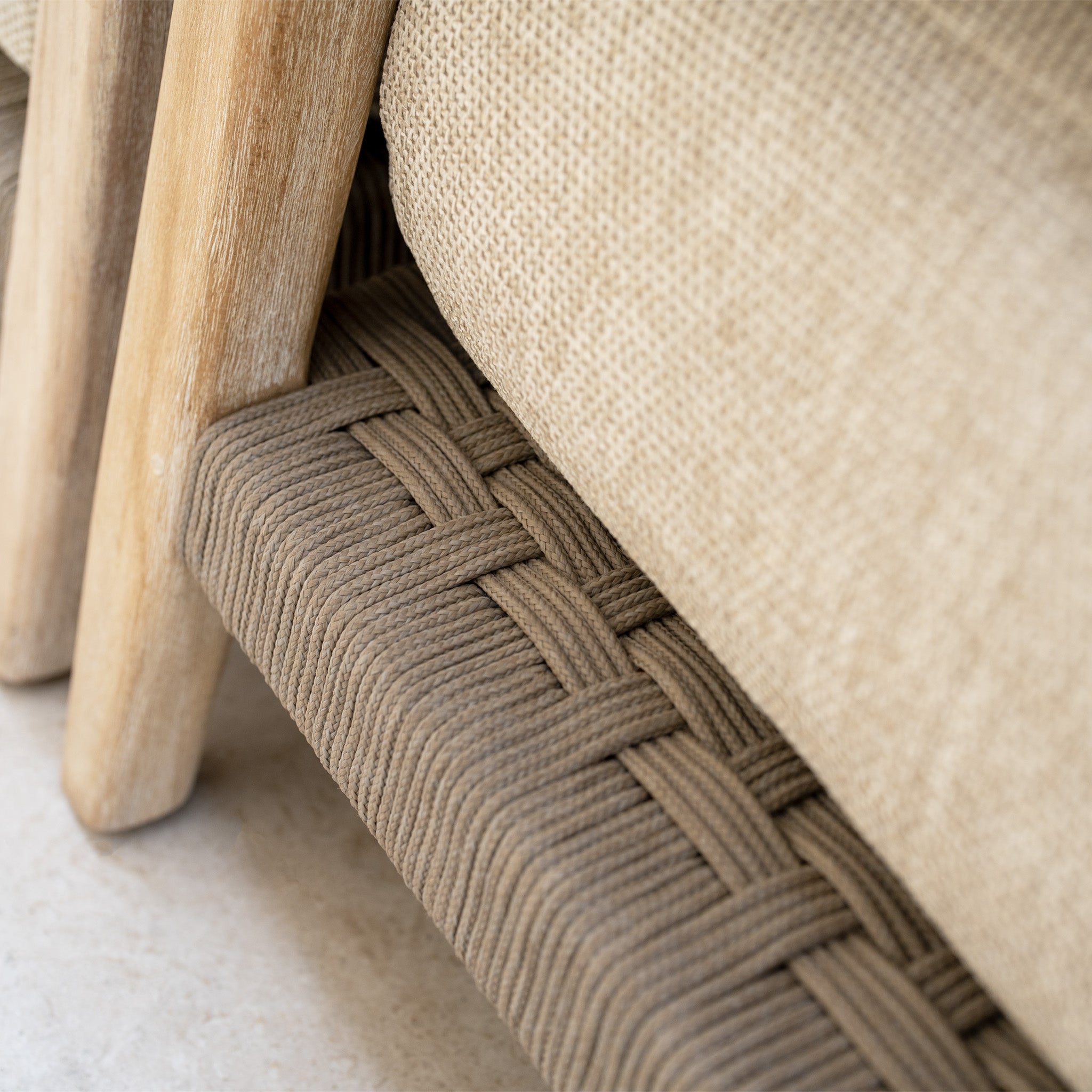 Close-up of woven rope detail and wooden frame on a beige cushioned chair from the Noah Corner Sofa Set with Armchair in Volga Grey, highlighting its rustic teak outdoor furniture craftsmanship.