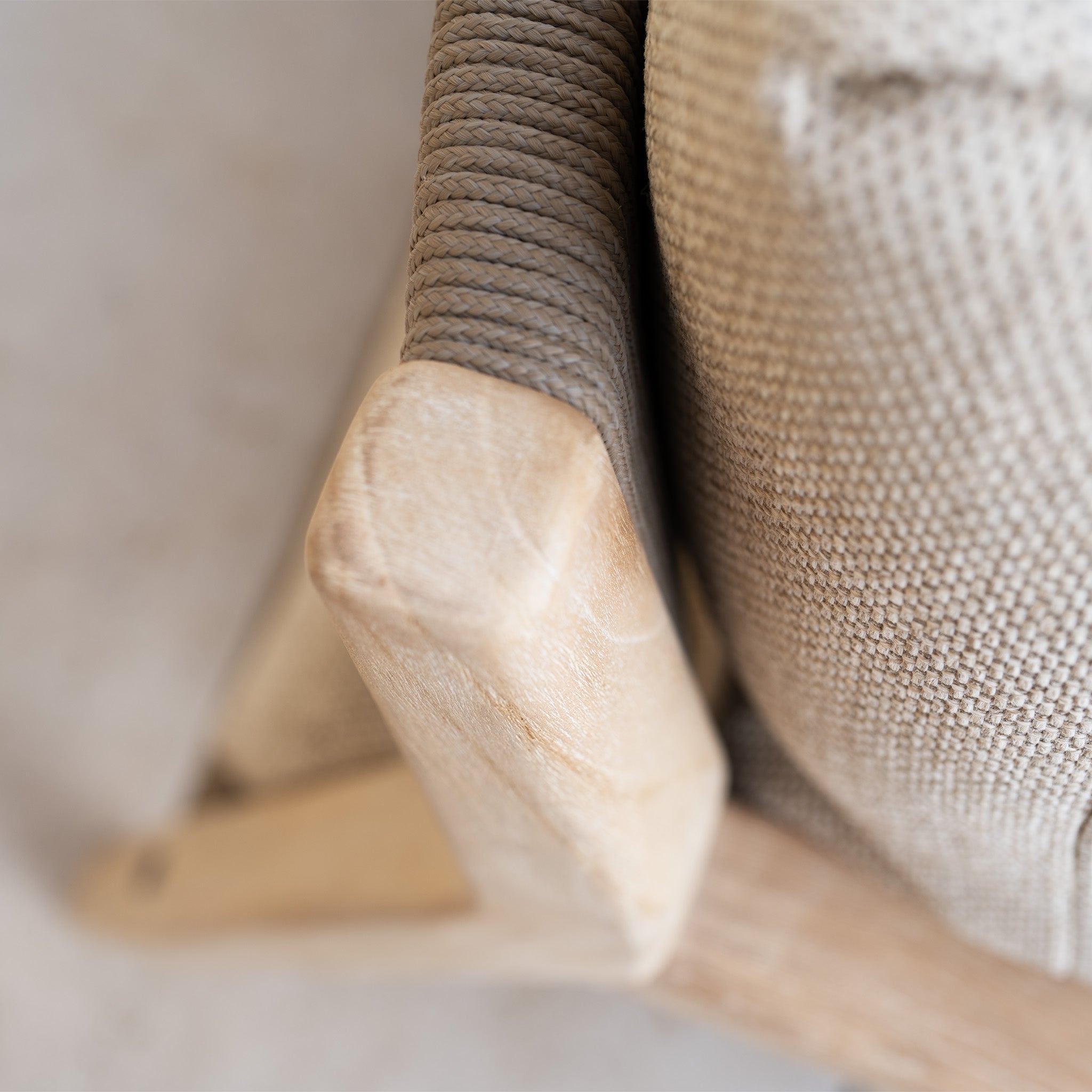 Close-up of the Noah Corner Sofa Set with Armchair in Volga Grey, featuring a wooden frame, textured beige upholstery, and woven rope details reminiscent of rustic teak outdoor craftsmanship.