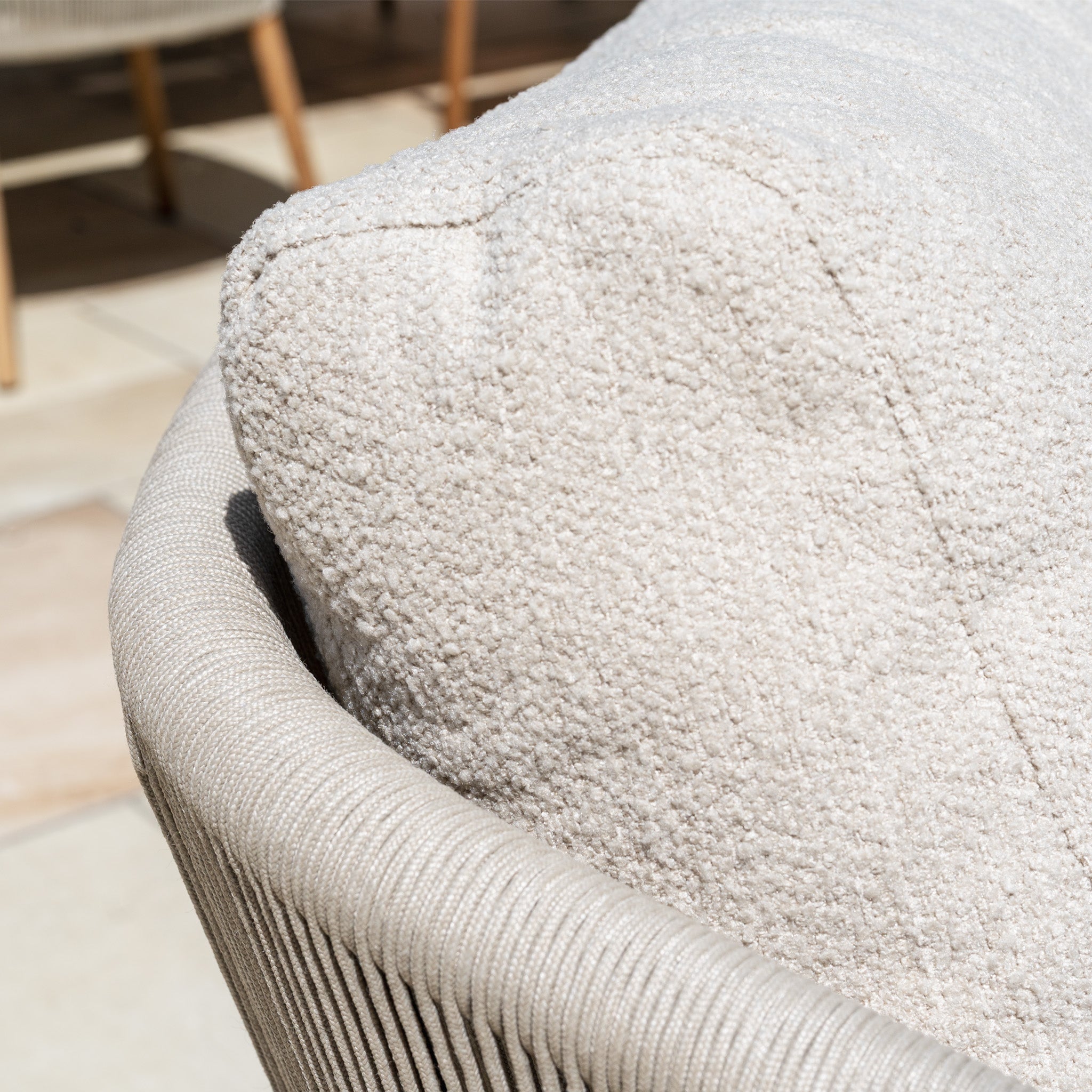 Close-up of a textured, light beige cushion from the New York 3 Seat Sofa Set on a woven chair in sunlight, showcasing weather-resistant furniture ideal for outdoor living.