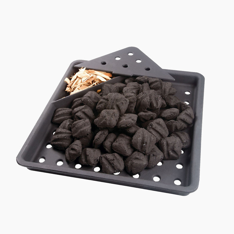 The Napoleon Cast Iron Charcoal & Smoker Tray, shown on a white background, holds a pile of charcoal briquettes and a section of wood chips.