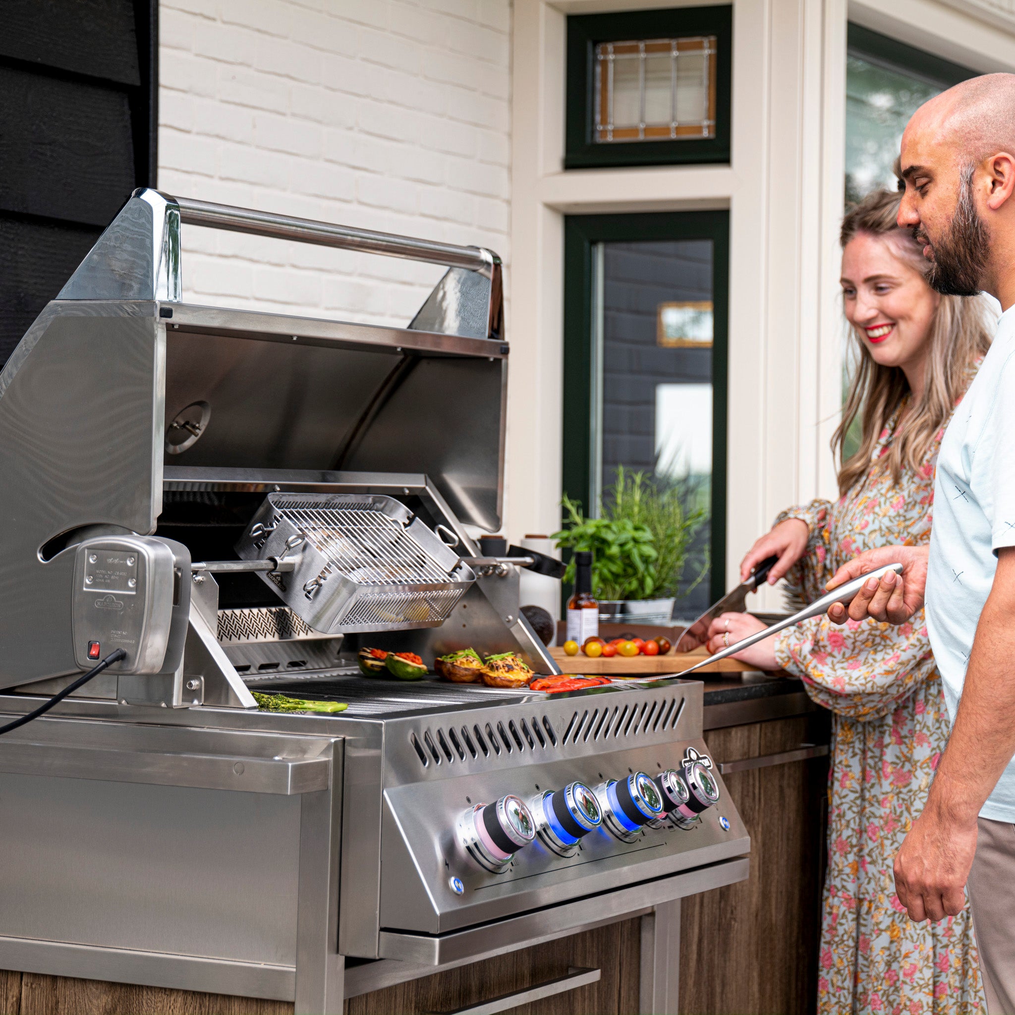 Two people are grilling assorted vegetables and kebabs on the Napoleon 700 Series 32" Built-in Gas Grill, featuring a sleek stainless steel finish and Rear Infrared Burner for an impeccable outdoor cooking experience.