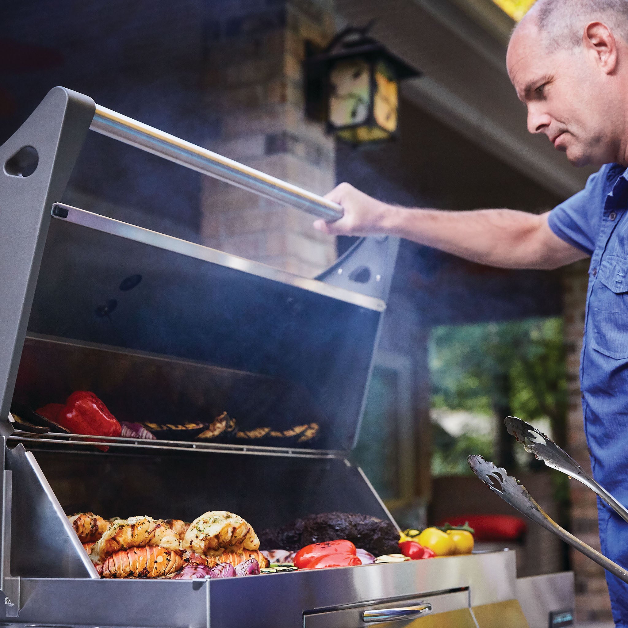 A person is expertly grilling an assortment of vegetables, meat, and seafood on a Napoleon Charcoal Professional Barbecue, using its stainless steel charcoal grill and charcoal-powered rotisserie burner for that perfect smoky flavor.