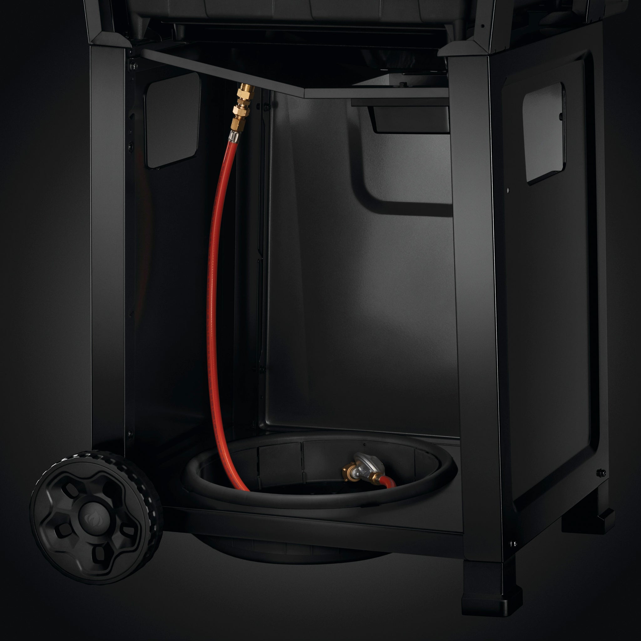 Close-up view of the lower section of a Napoleon Freestyle 425 Gas Barbecue, featuring a red hose, circular compartment, and cast iron porcelainized enamel cooking grids.