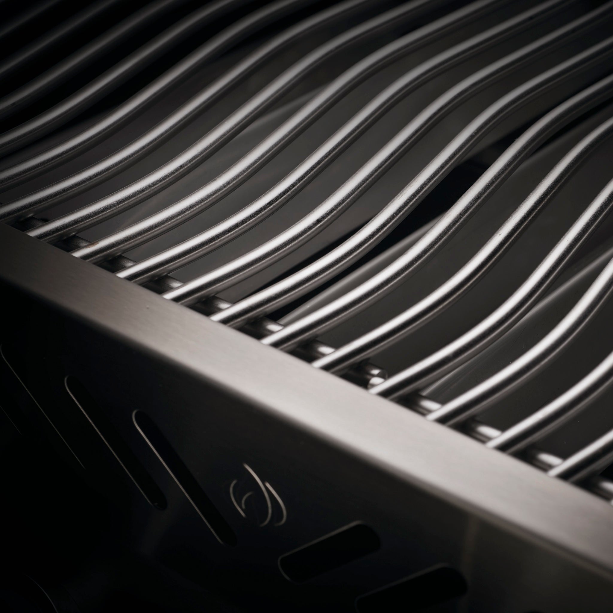 Close-up of a stainless steel grill grate with parallel metal bars and a curved edge, showcasing a sleek and modern design. This Napoleon Prestige 500 RSIB Gas Barbecue features infrared side and rear burners for exceptional cooking versatility.