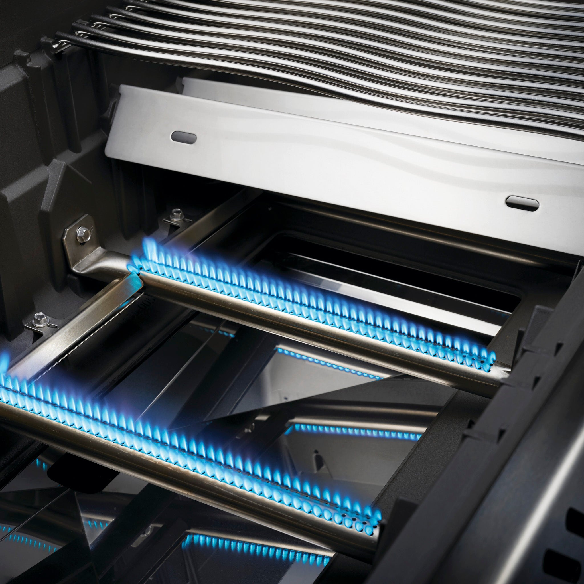 Close-up view of a Napoleon Rogue XT 365 SIB Gas Barbecue with blue flames burning from its stainless steel burners and cast iron grids.