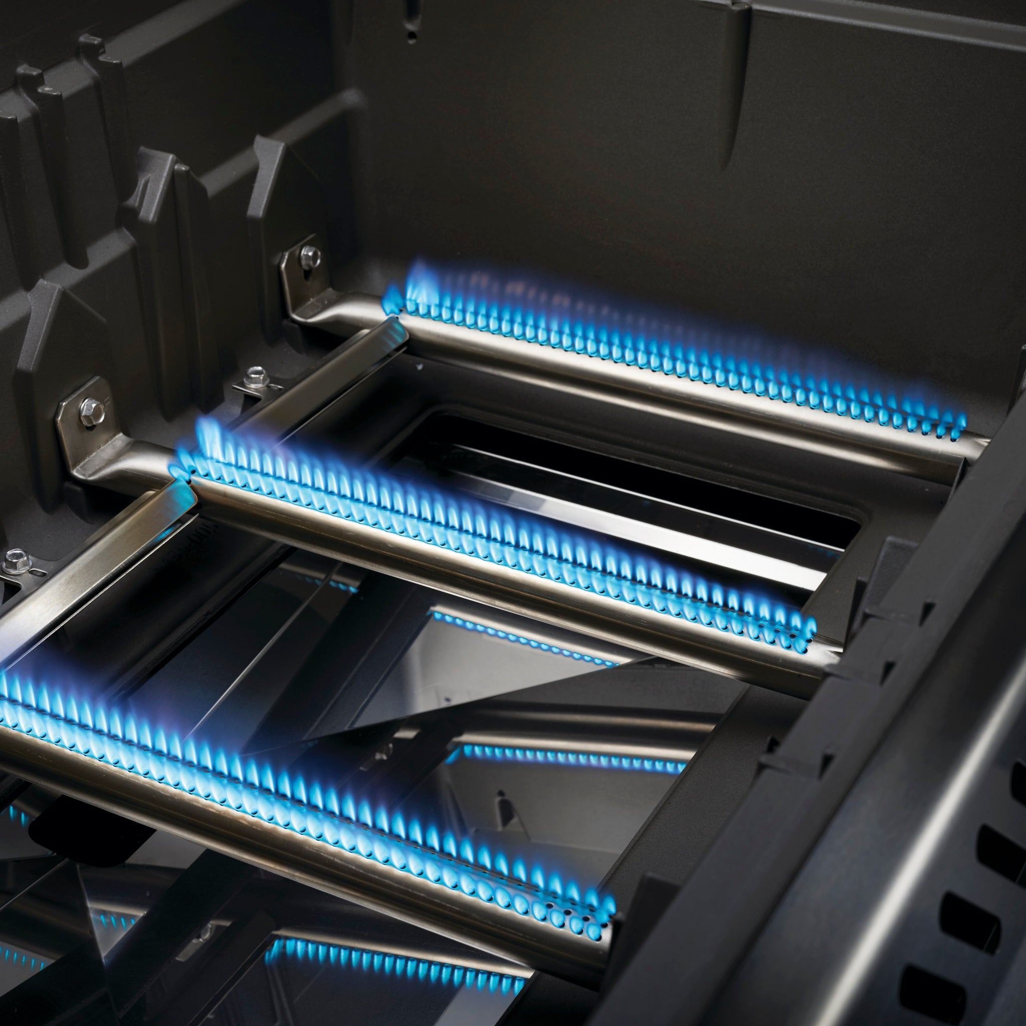Close-up of a Napoleon Rogue SE 625 RSIB Gas Barbecue with blue flames burning on metal burner tubes.