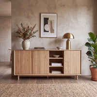 Minimalist Oslo 3 Door Sideboard with Shelves in Light Oak, styled with decor pieces including a gold lamp, vase with dried plants, art print, and potted plant. This sideboard features adjustable shelving for versatile storage while maintaining a clean, modern aesthetic.