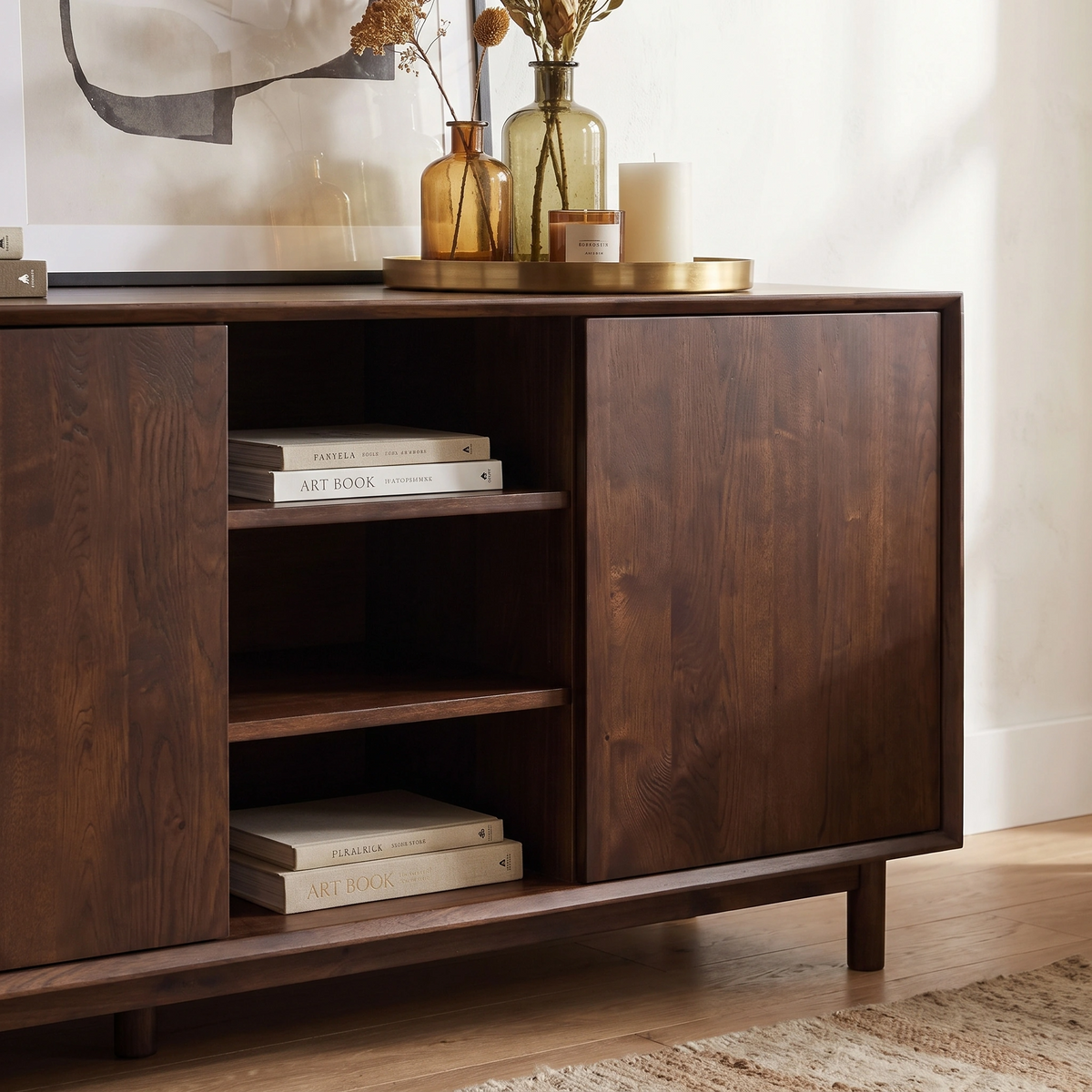 Oslo 3 Door Sideboard with Shelves in Walnut styled with decorative accents, art books, and vases on top, placed against a light-colored wall.