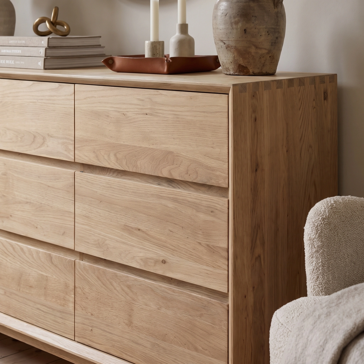 Light oak Oslo 9 Drawer Chest with ample storage, styled with decor items, books, candles, and a ceramic vase on top—a perfect blend of elegance and functionality for your bedroom inspired by timeless Scandinavian design.