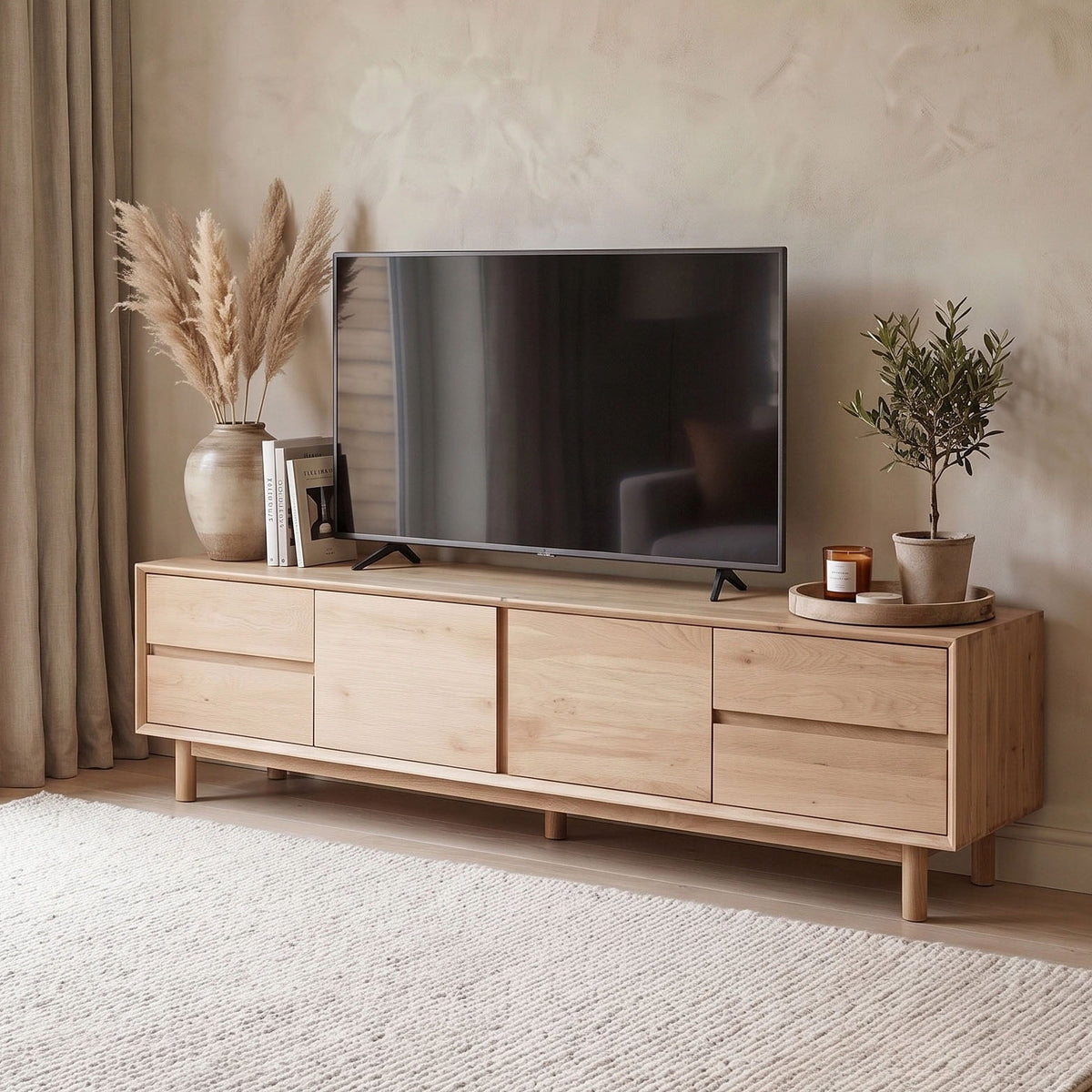 A flatscreen TV sits on the Oslo TV Unit in Light Oak, surrounded by vases, pampas grass, a plant, and candles in a cozy room.