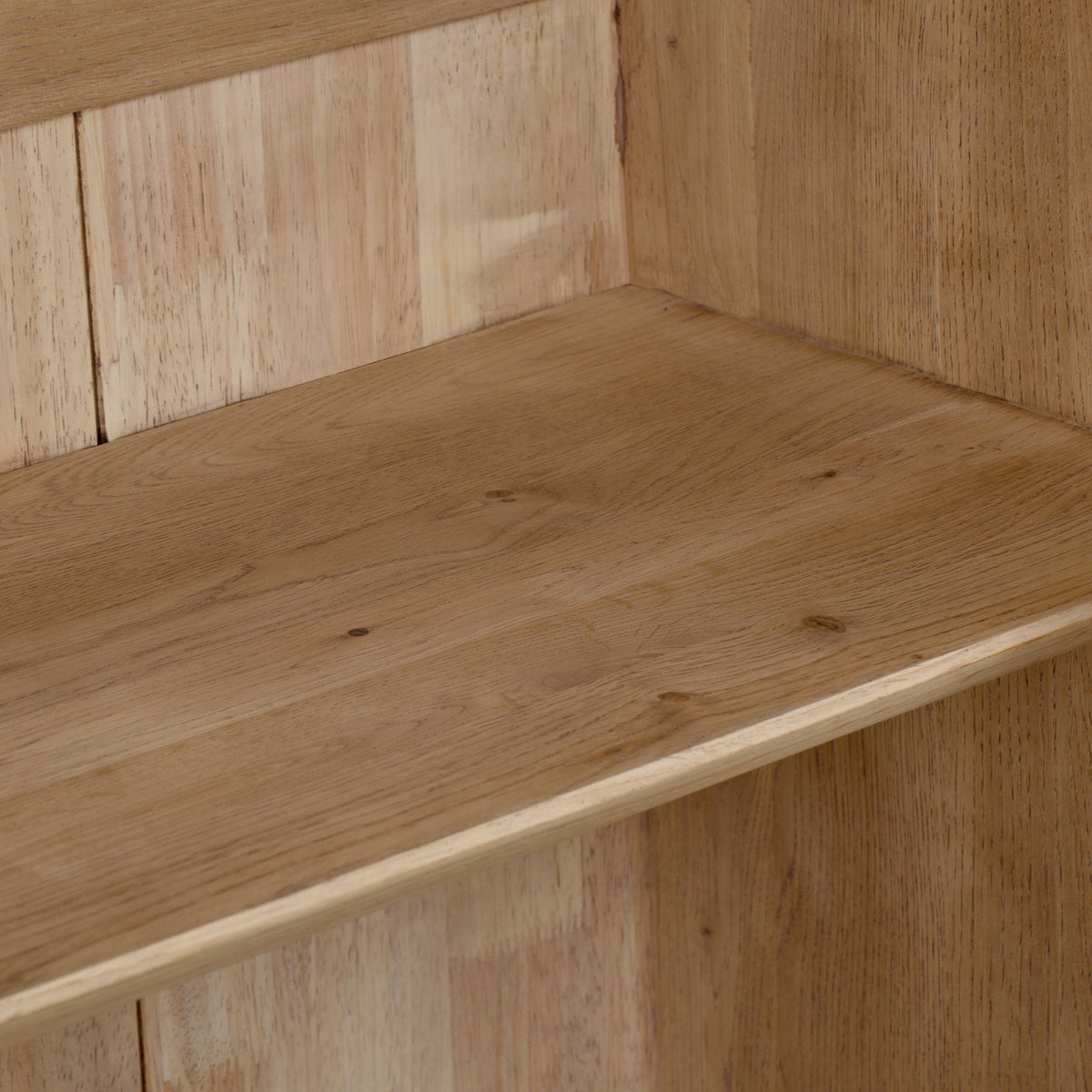 Close-up of a light brown wooden shelf with visible wood grain and a vertical wood panel background, highlighting the refined craftsmanship of the Oslo Display Cabinet in Light Oak.