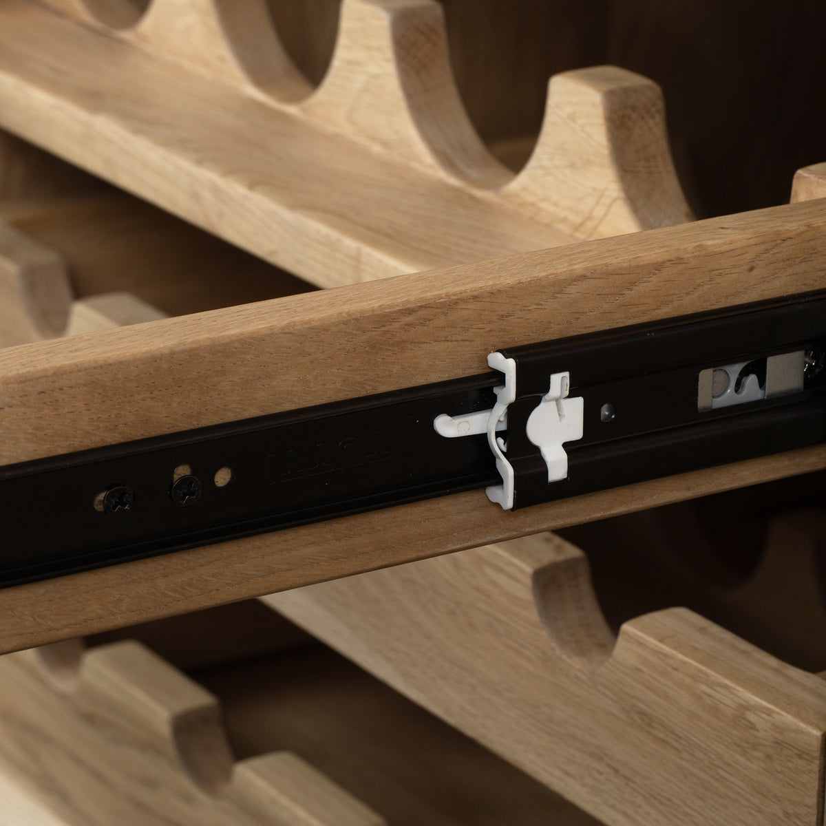 Close-up of the Oslo Grand 4 Door Sideboard with Wine Rack in Light Oak, featuring solid oak craftsmanship, a black metal rail, and a small white plastic latch.