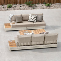 Two modern Panama 3 Seat Sofas with Sun Lounger Feature in Latte, featuring beige cushions and wooden accents, are arranged on a patio next to a wooden table.