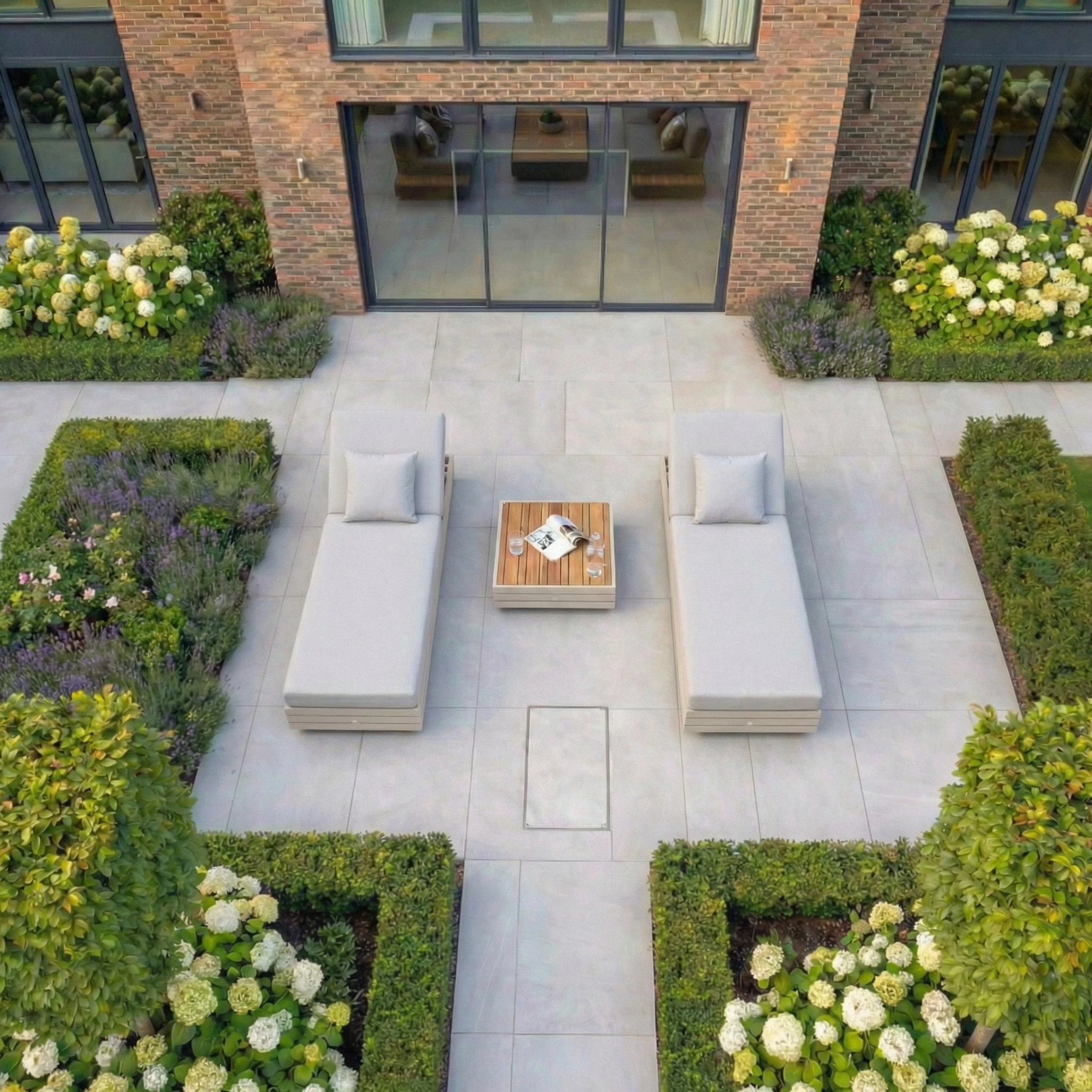 Modern patio featuring the Panama 3 Seat Sofa with Sun Lounger Feature in Latte, arranged for relaxing with a wood table set for drinks and magazines.