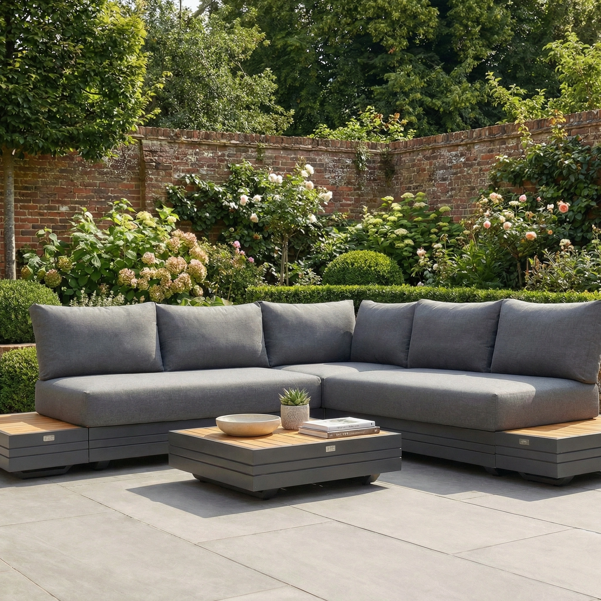 Panama Luxury Outdoor Corner Group Set in Charcoal with a low coffee table on the patio, surrounded by lush garden and brick wall—a sophisticated modular sofa set for stylish outdoor living.