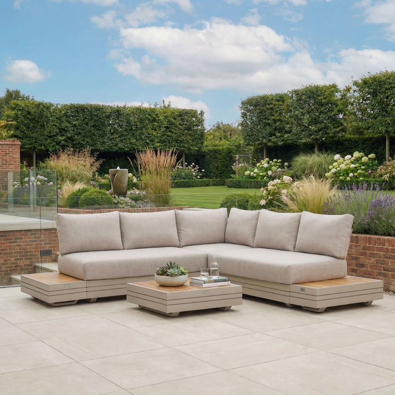 Modern outdoor patio featuring the Panama Luxury Outdoor Corner Group Set in Latte with a low table and lush green garden in the background.