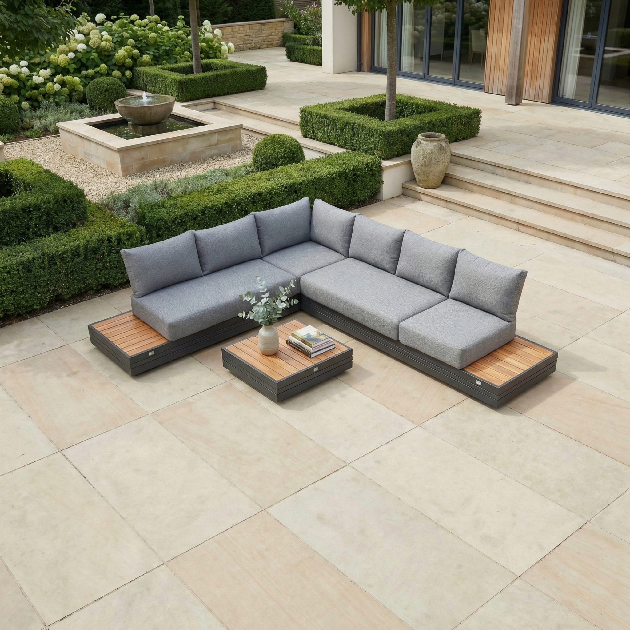Modern outdoor patio featuring the Panama Luxury Outdoor L-Shape Corner Group Set in Washed Grey, a low table, and lush landscaping—blending stylish garden furniture with ultimate comfort.